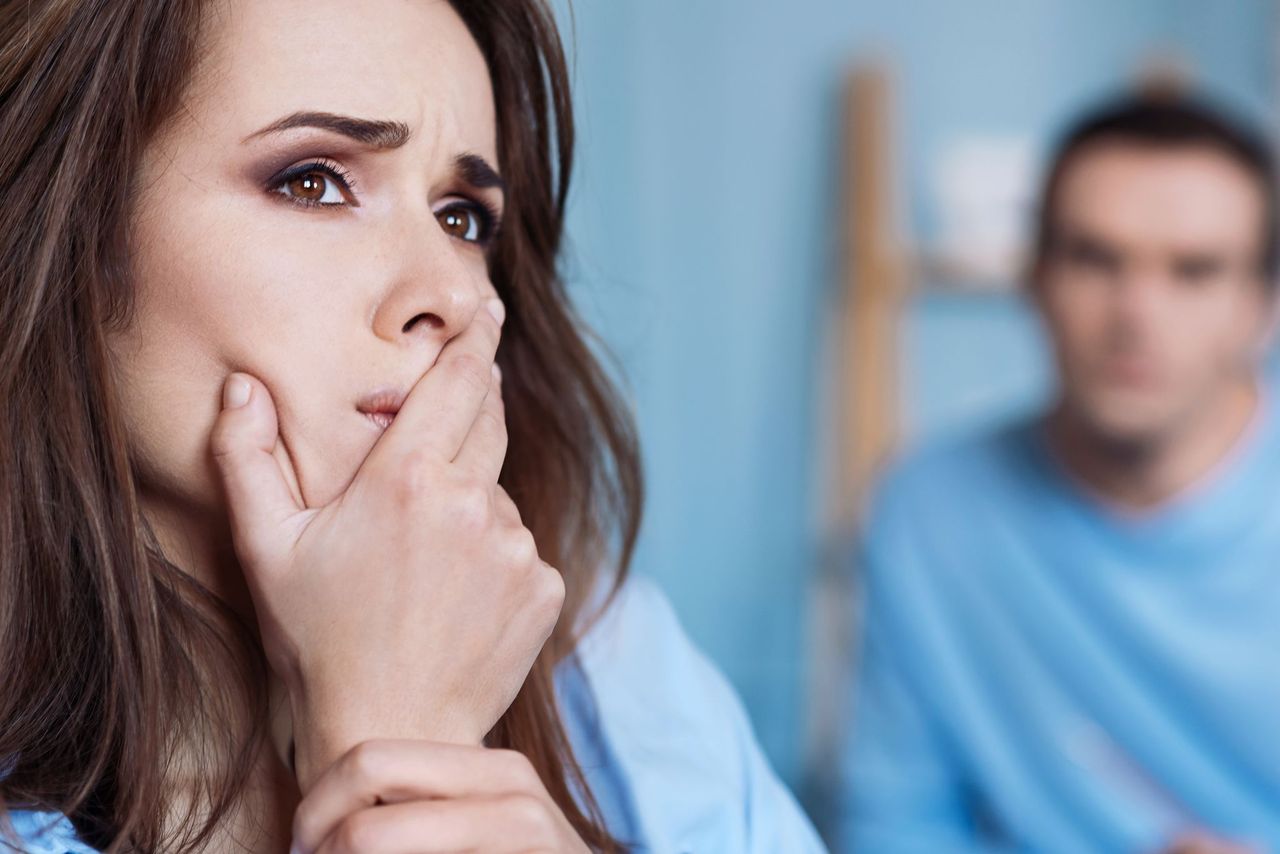 A woman looks disappointed while a man sits from behind. | Source: Shutterstock