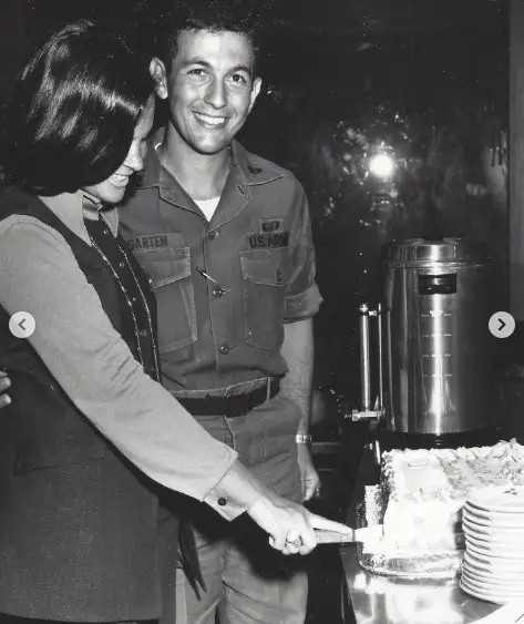 Ina and Jeffrey Garten share a joyful moment as Ina cuts a cake, with Jeffrey in uniform smiling beside her. This early glimpse into their marriage reflects the warmth and support that has defined their enduring five-decade relationship. | Source: Instagram/inagarten