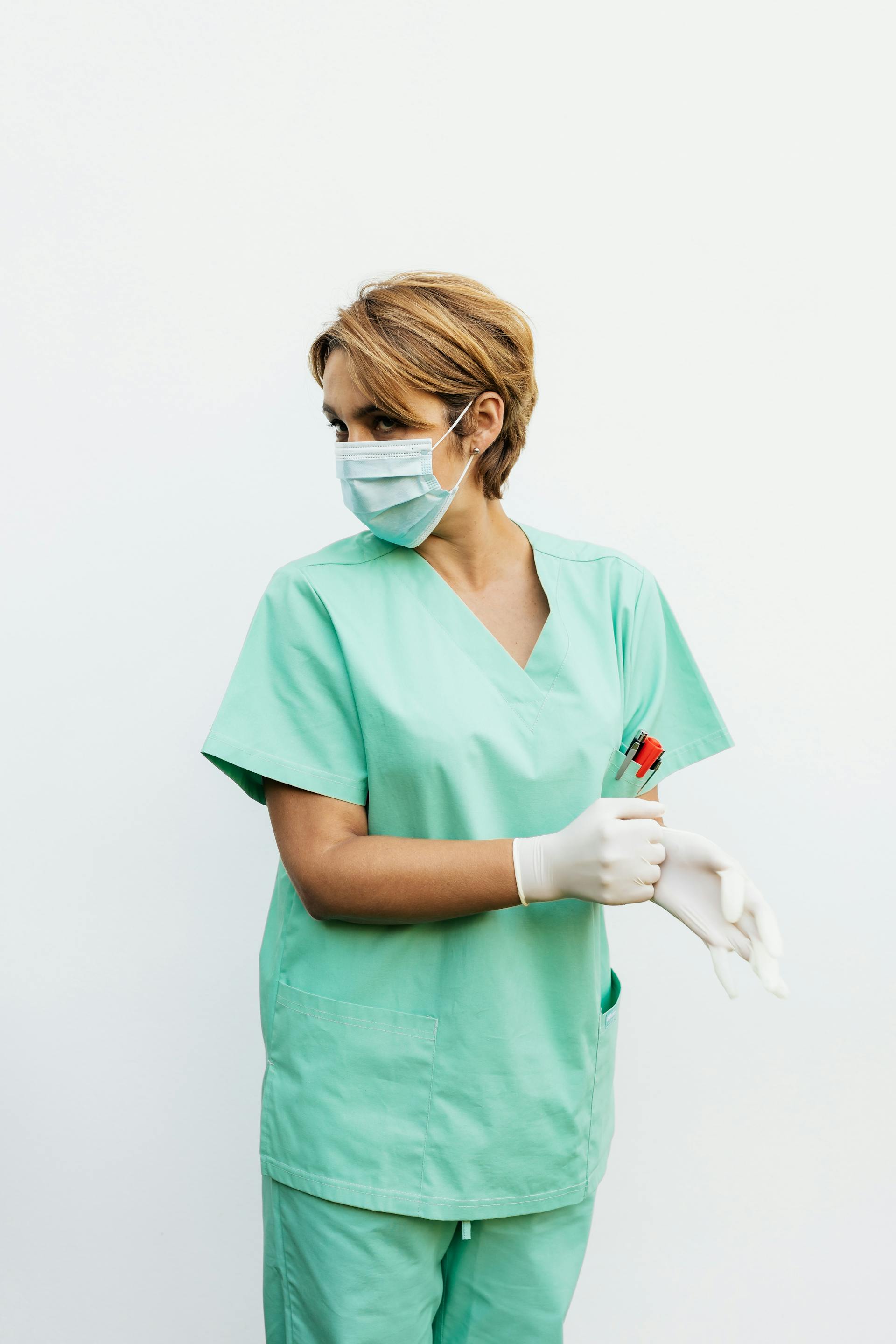 A nurse in scrubs and face mask looking back | Source: Pexels