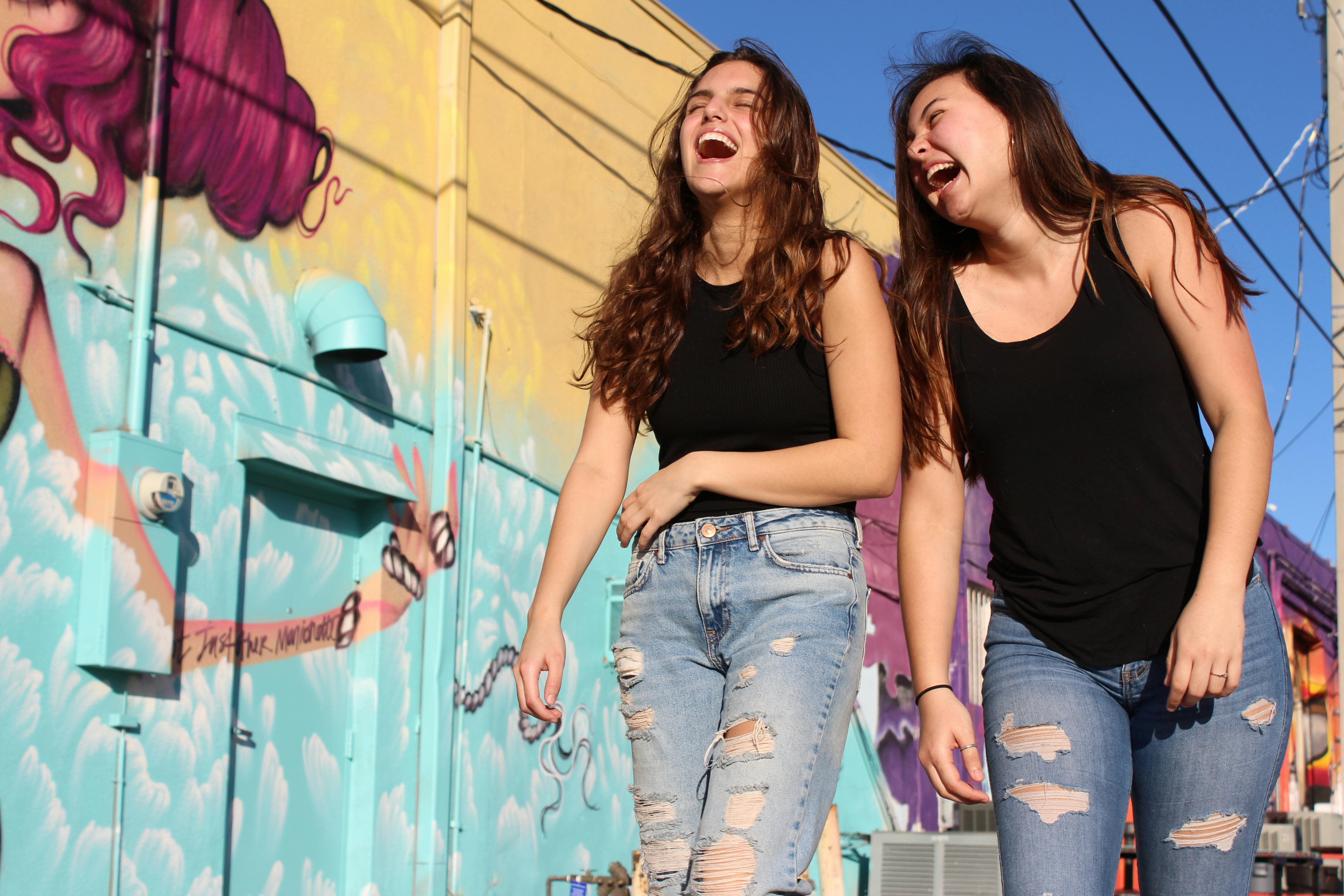 Two young women walking and laughing | Source: Savannah Dematteo on Pexels