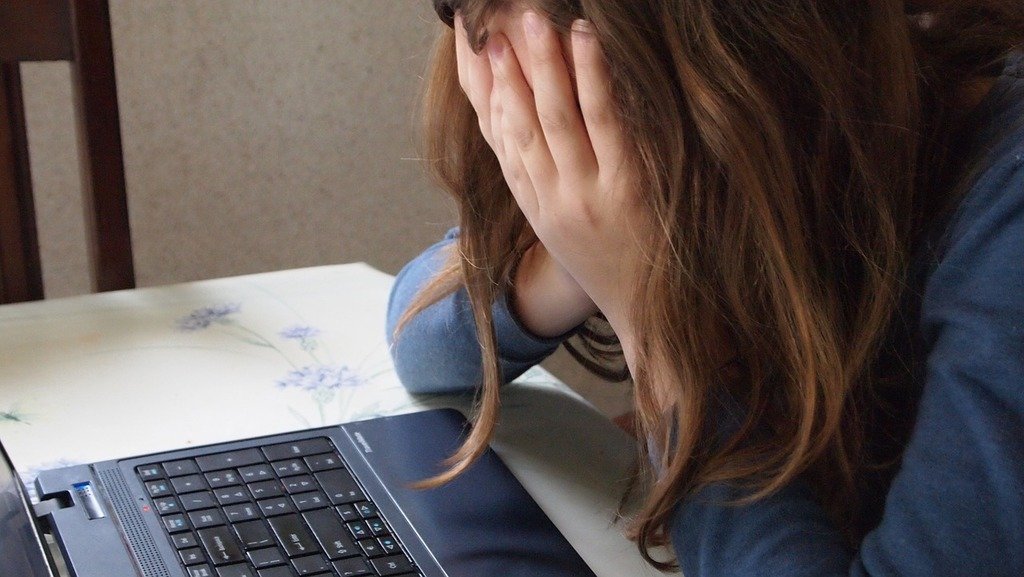 Chica agobiada frente a una computadora. | Foto: Picryl