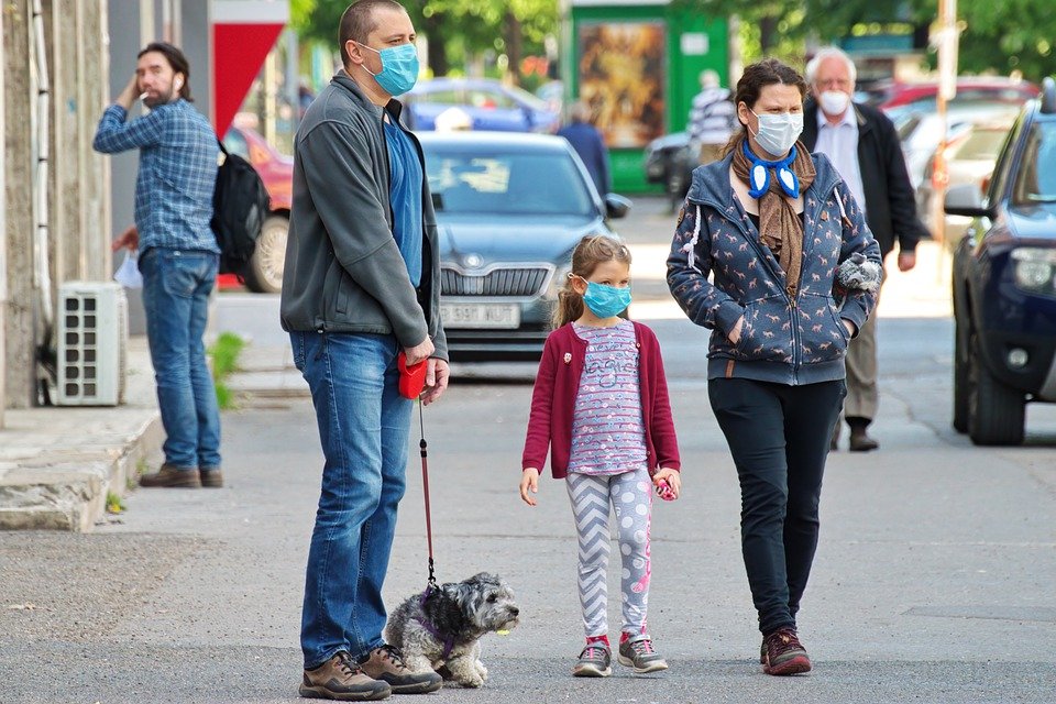 Padres en la calle con su hija y su mascota, todos usan mascarilla para protegerse. | Foto: Pixabay