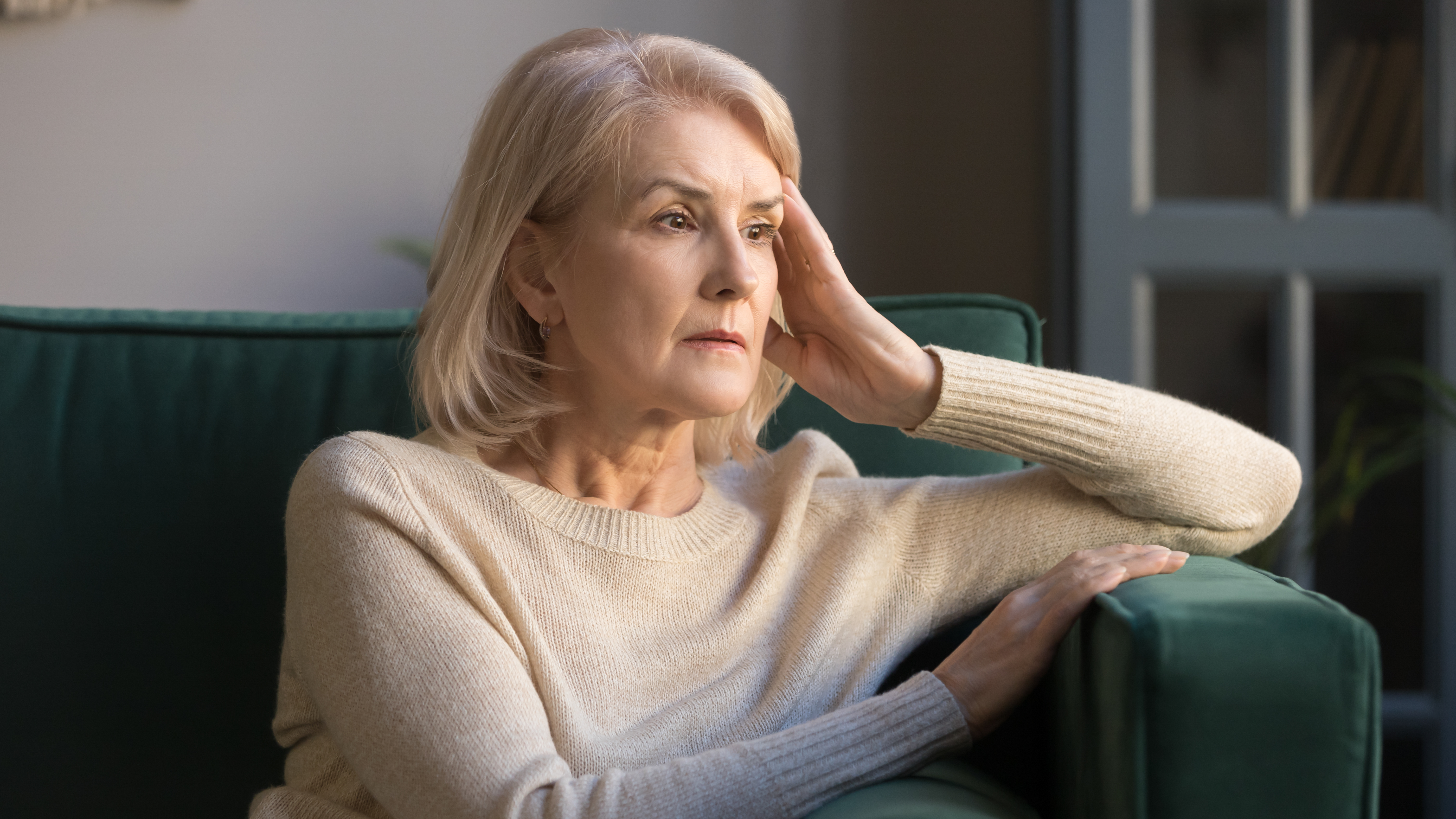 A depressed senior woman sitting on a sofa | Source: Shutterstock