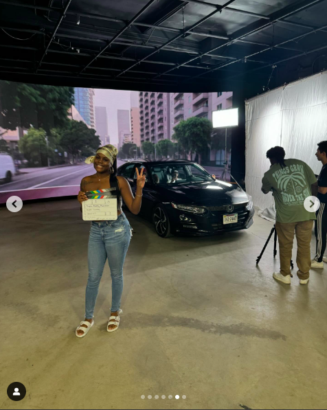 Alysha Burney posing with an action slate on set as production crew members work in the background. | Source: Instagram/alyshaburney_