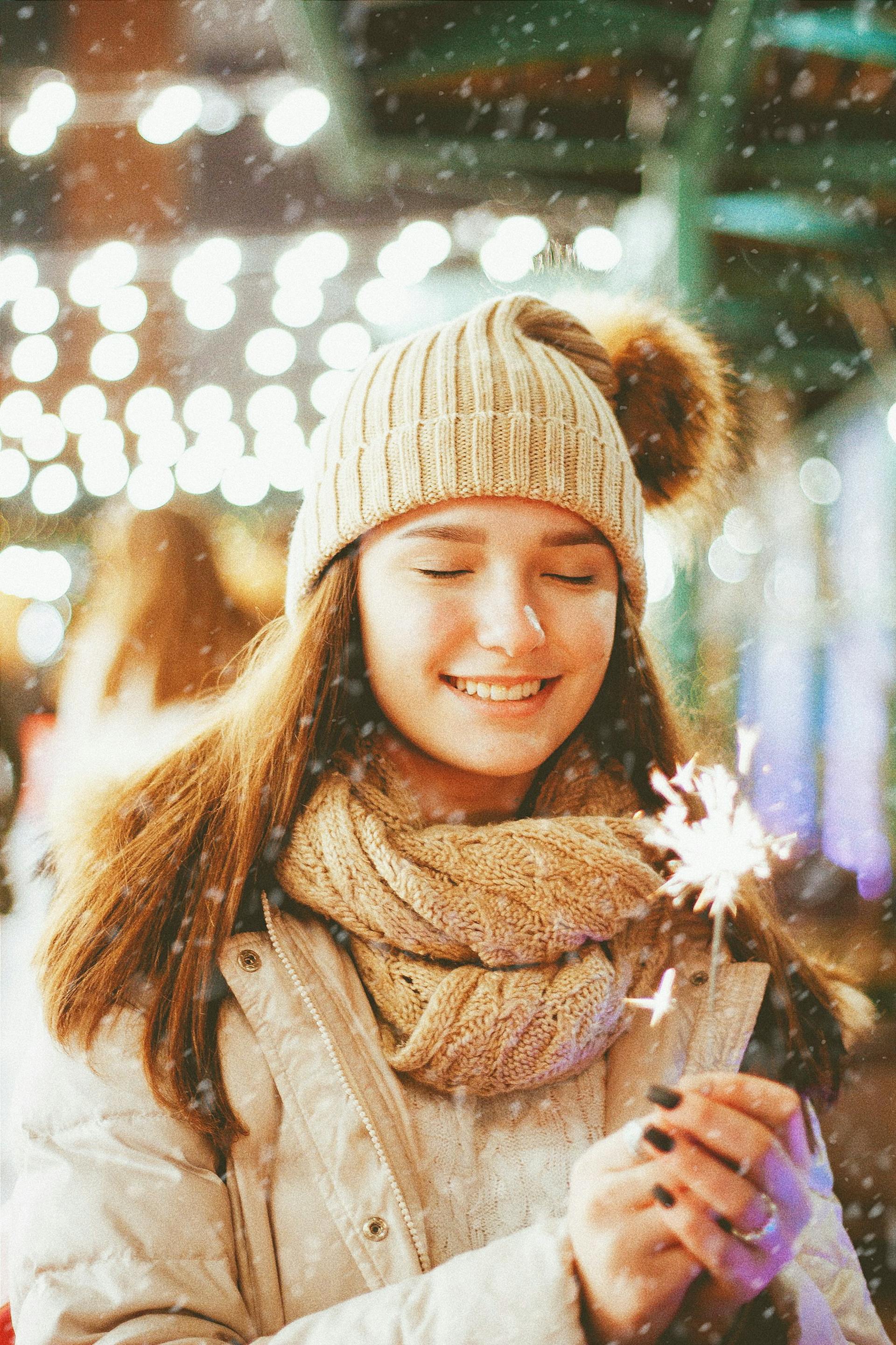 A teenage girl dressed in winter clothes holding a sparkler in her hands | Source: Pexels