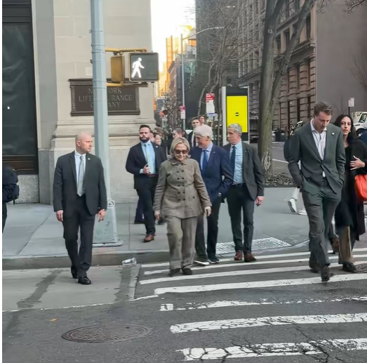 Hillary Clinton and Bill Clinton cross a zebra-striped crosswalk with aides and security after the pedestrian signal changes. | Source: TikTok/elderordonez