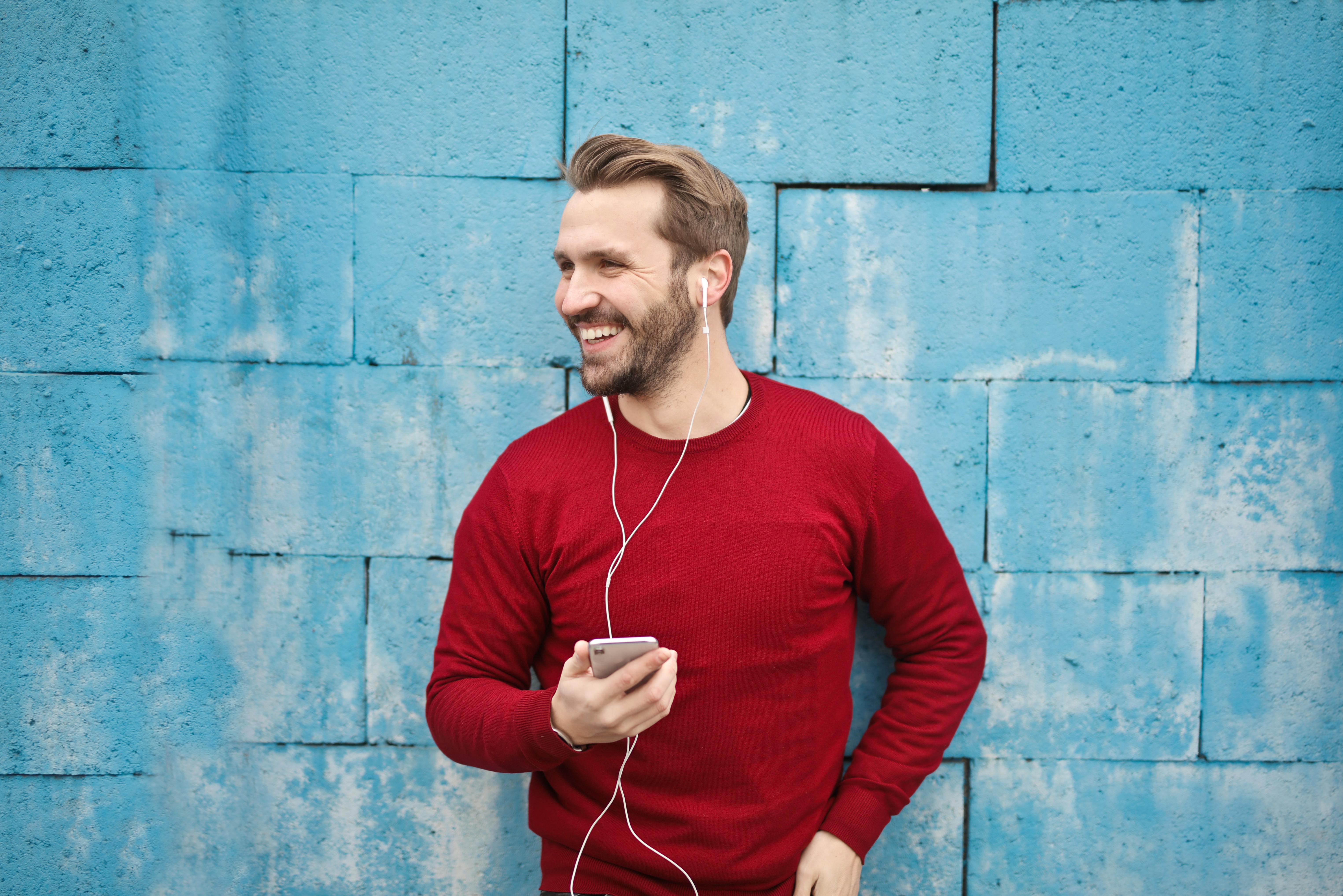 A happy man speaking on his phone through headsets | Source: Pexels
