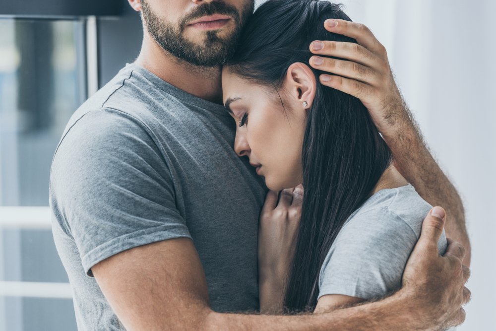 A cropped shot of a bearded man hugging and comforting a sad woman | Photo: Shutterstock/LightField Studios