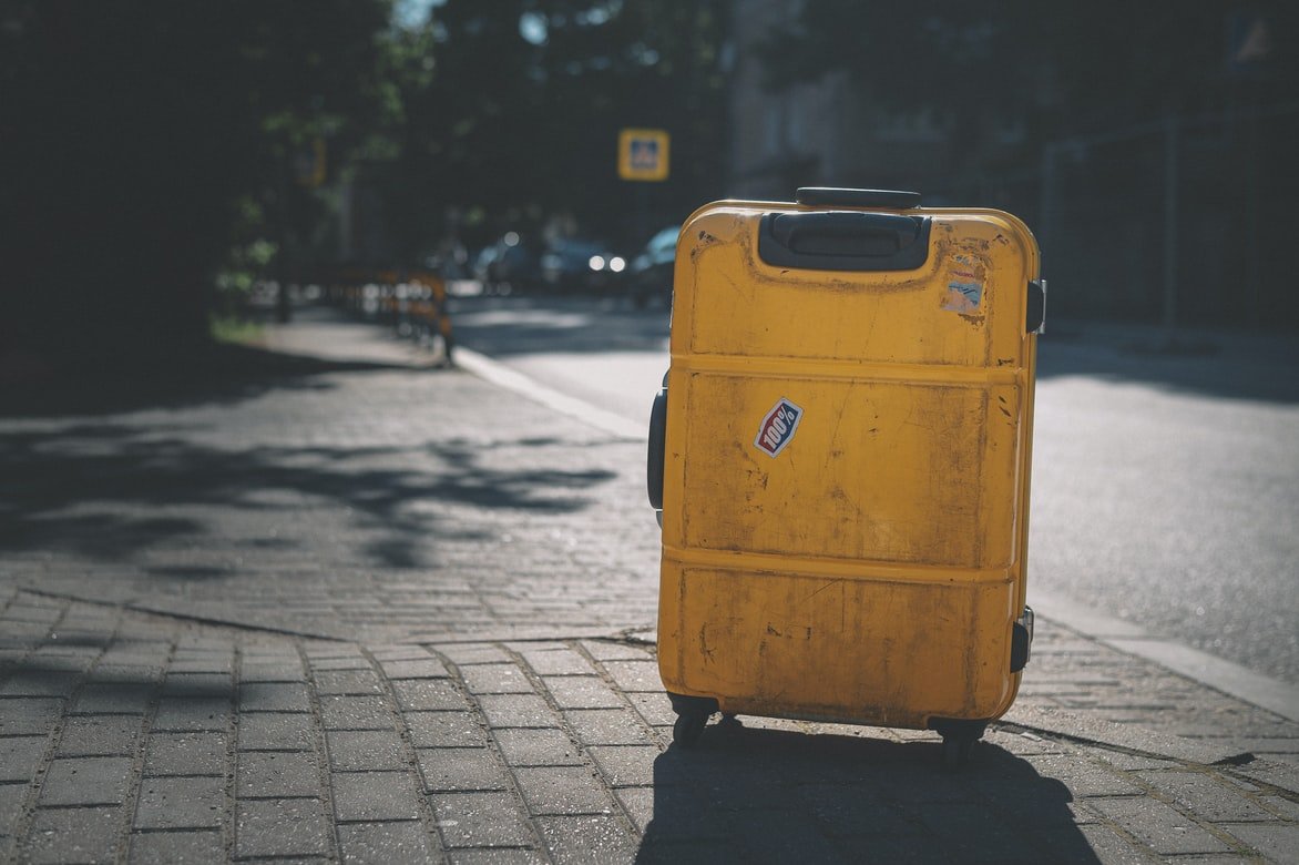 Una maleta amarilla en la mitad de una acera. | Foto: Unsplash