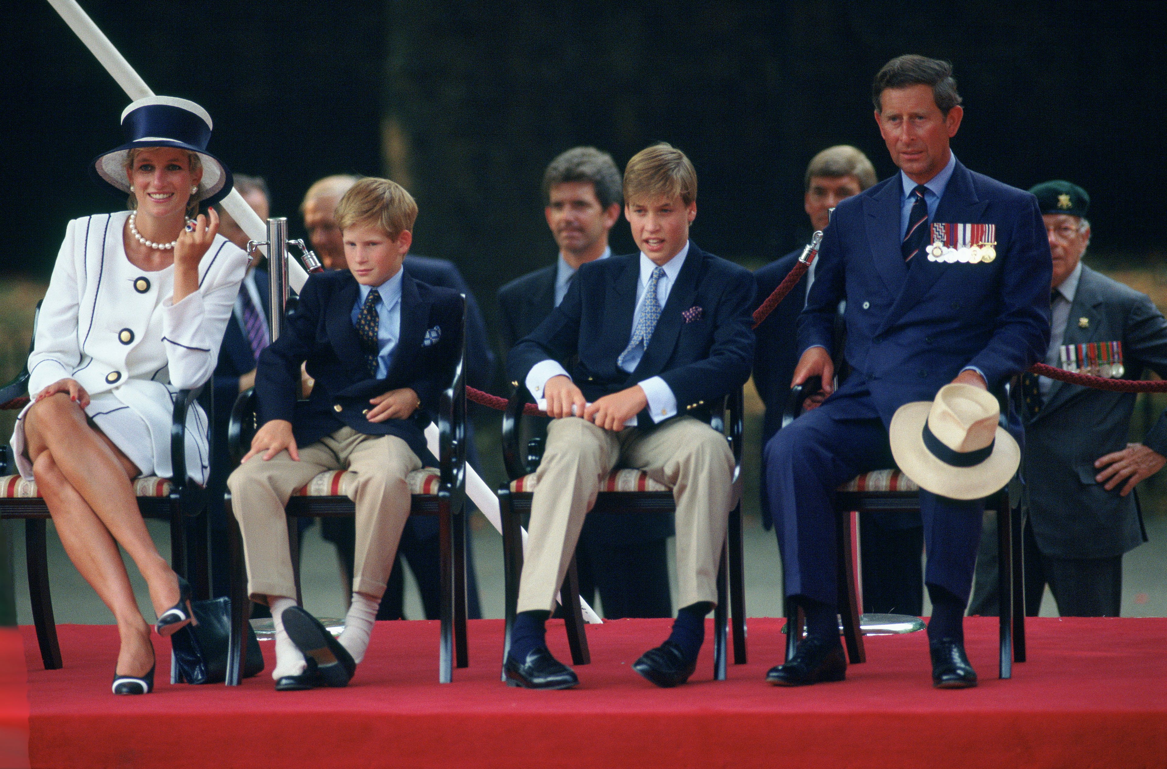 Prinz Harry hat seine Schuhe ausgezogen, während er die Parade zum 50-jährigen Jubiläum des Vj Day verfolgte. Er sitzt mit seiner Familie zusammen - Diana, Prinzessin von Wales, Prinz Charles und Prinz William. | Quelle: Getty Images
