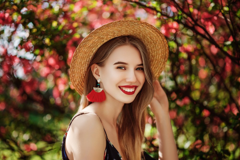 Mujer rodeada de naturaleza usando pendientes grandes de color rojo. | Foto: Shutterstock