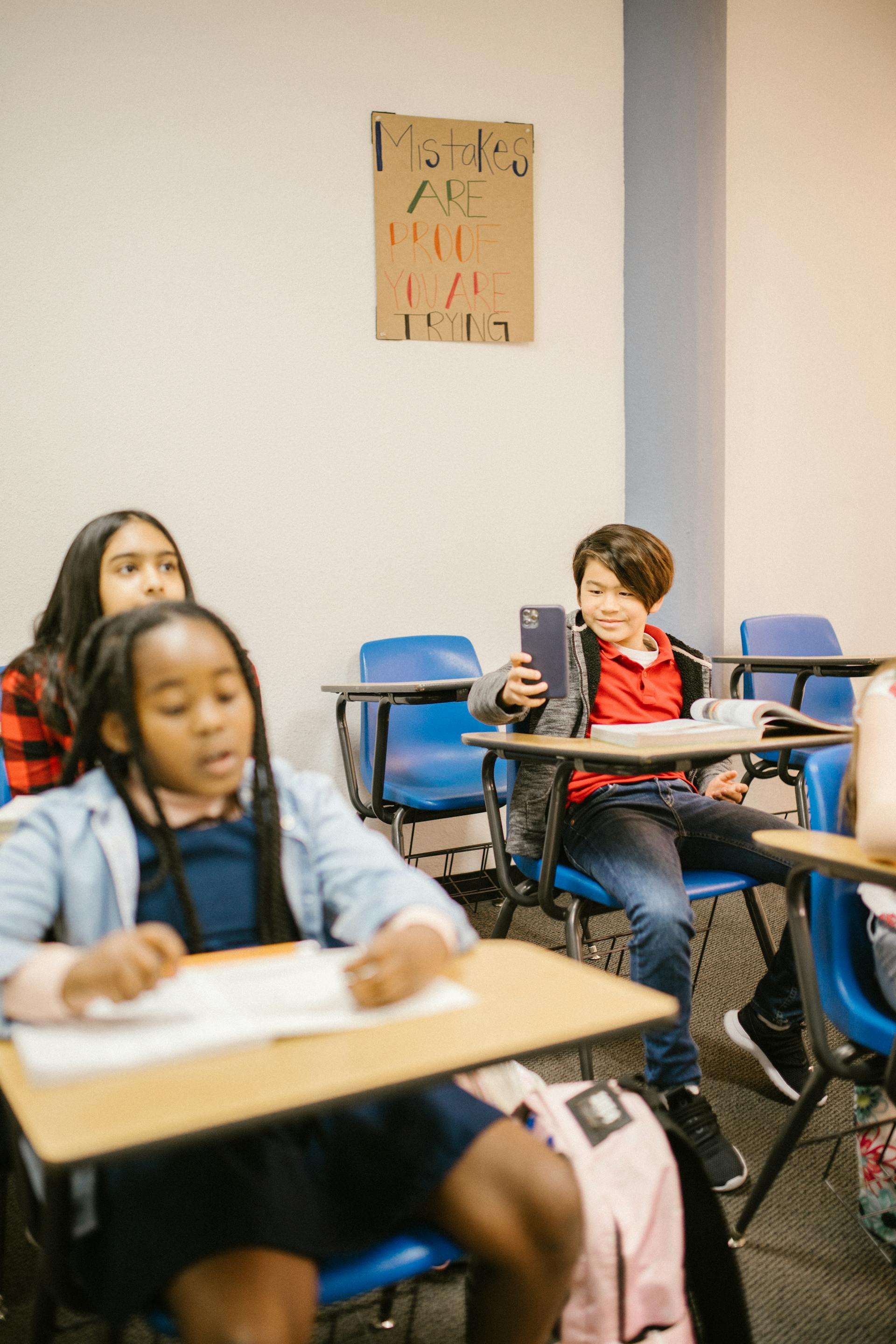 A boy in a classroom using a cell phone | Source: Pexels