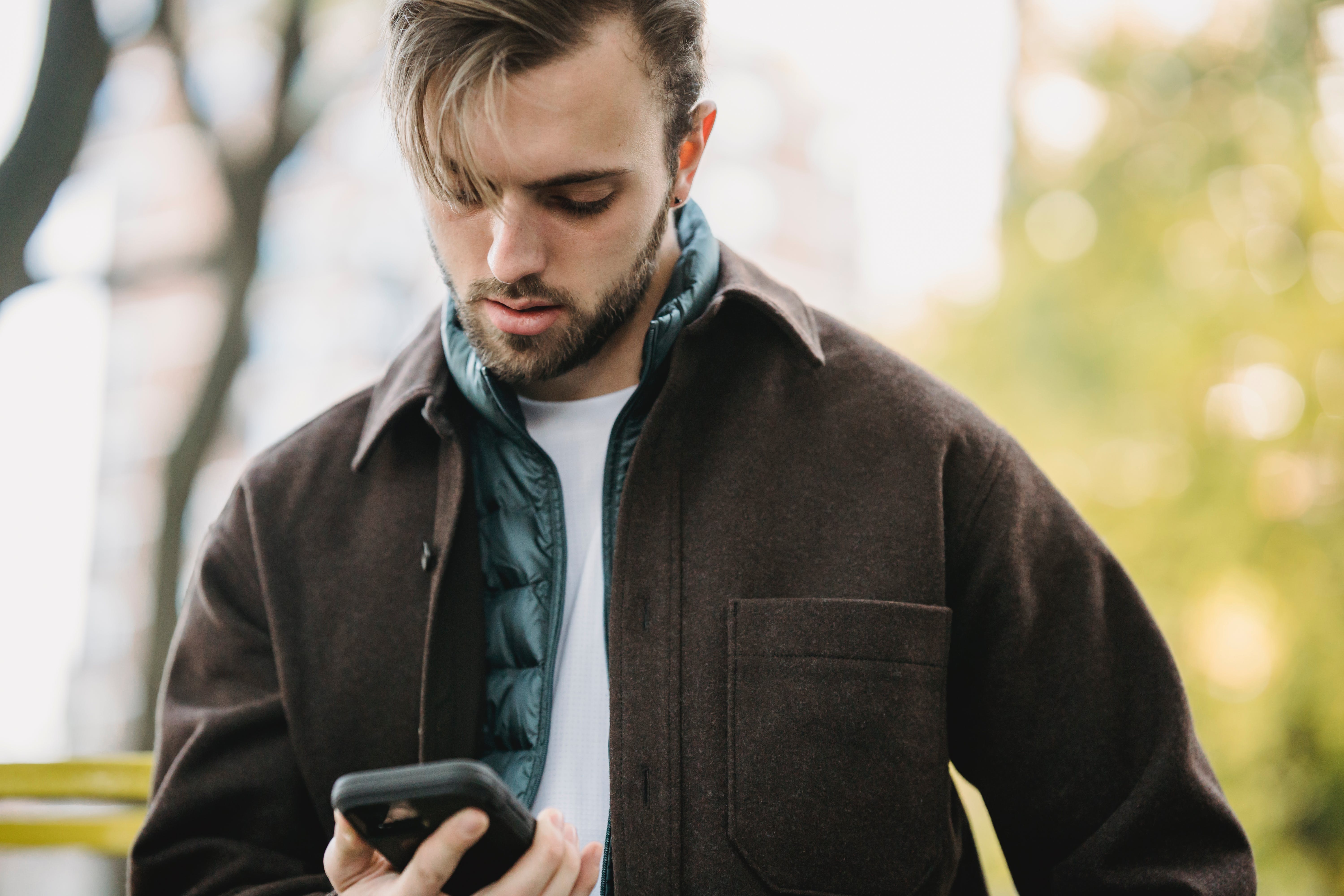 A man looking down at his cell phone while outside | Source: Pexels
