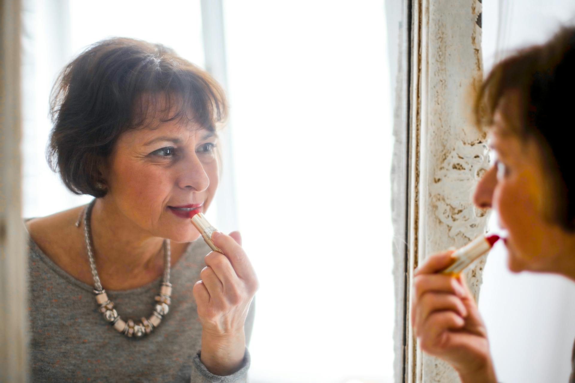 An older woman applying lipstick | Source: Pexels