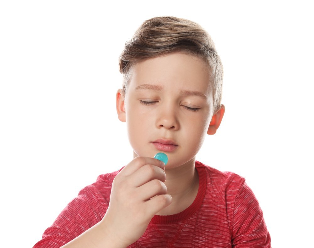 A little boy licking a piece of candy. | Photo: Shutterstock