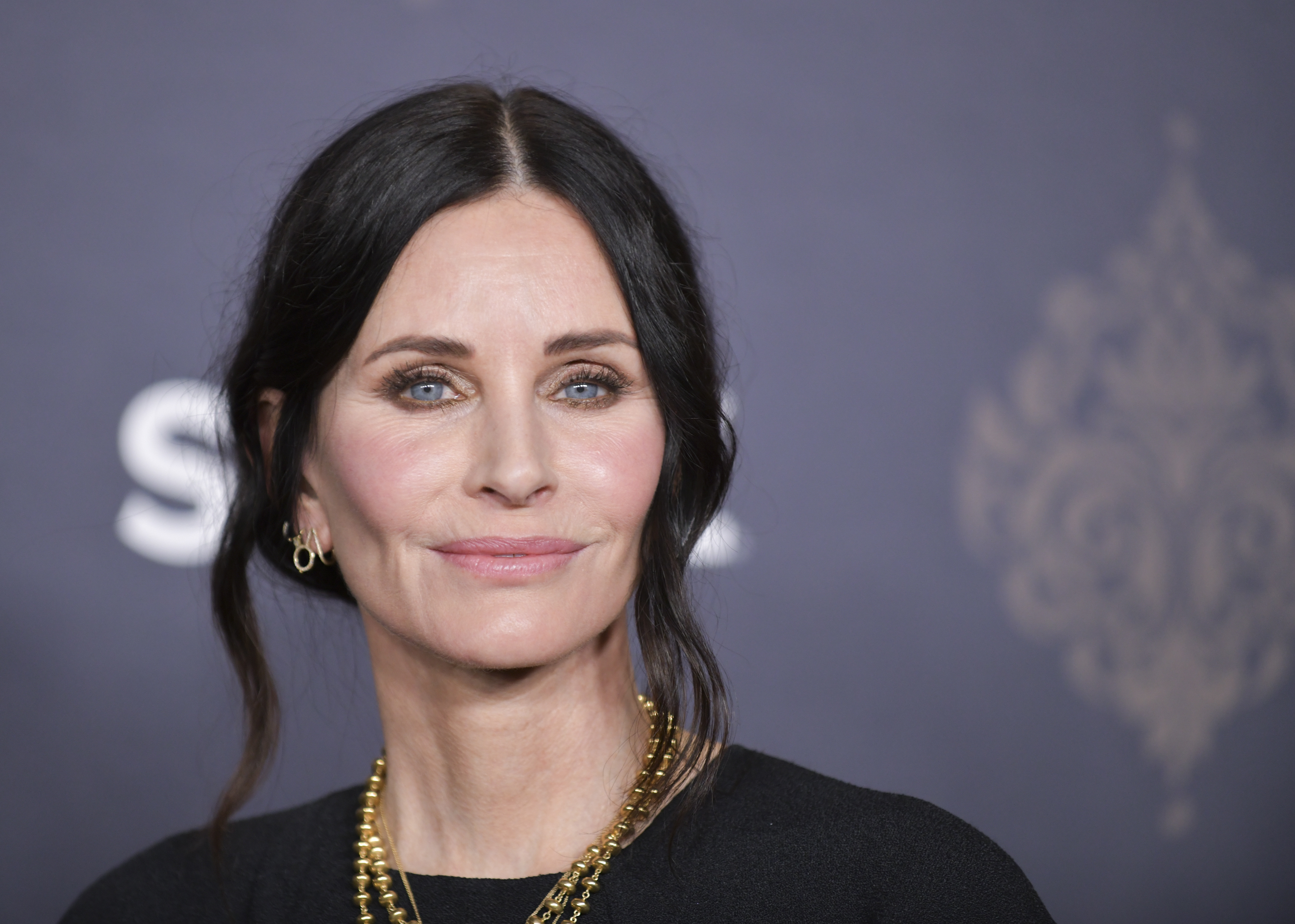 Courteney Cox showcases her post-pandemic style at the "Shining Vale" premiere on February 28, 2022, at TCL Chinese Theatre in Hollywood, sporting bright blush, a soft pale pink look, and gold jewelry accents.