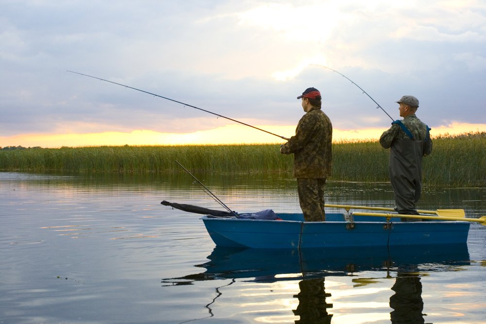 Two men on a boat fishing. | Photo: Shutterstock.