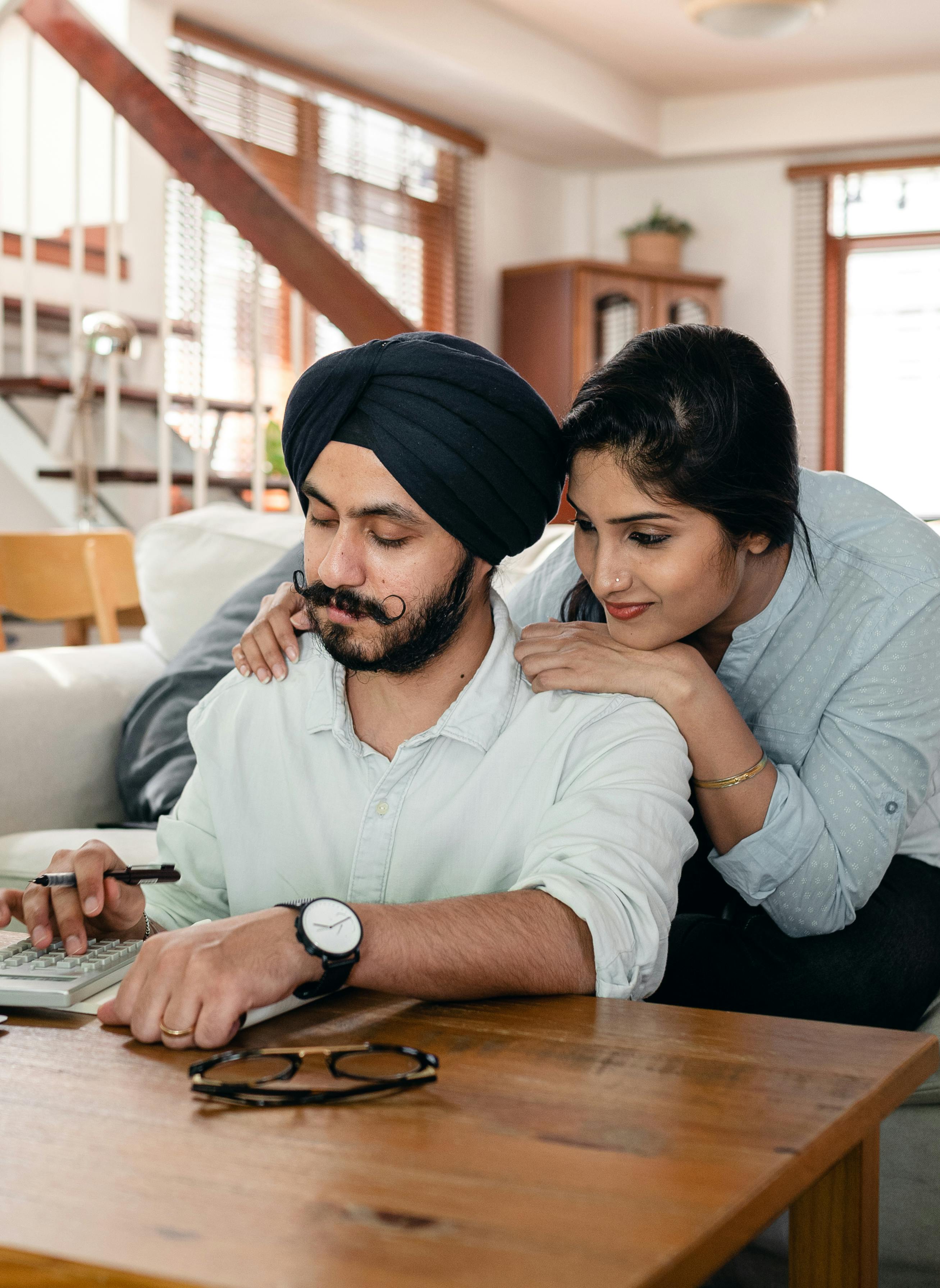 A man punching on a calculator as a woman leans on him from behind | Source: Pexels