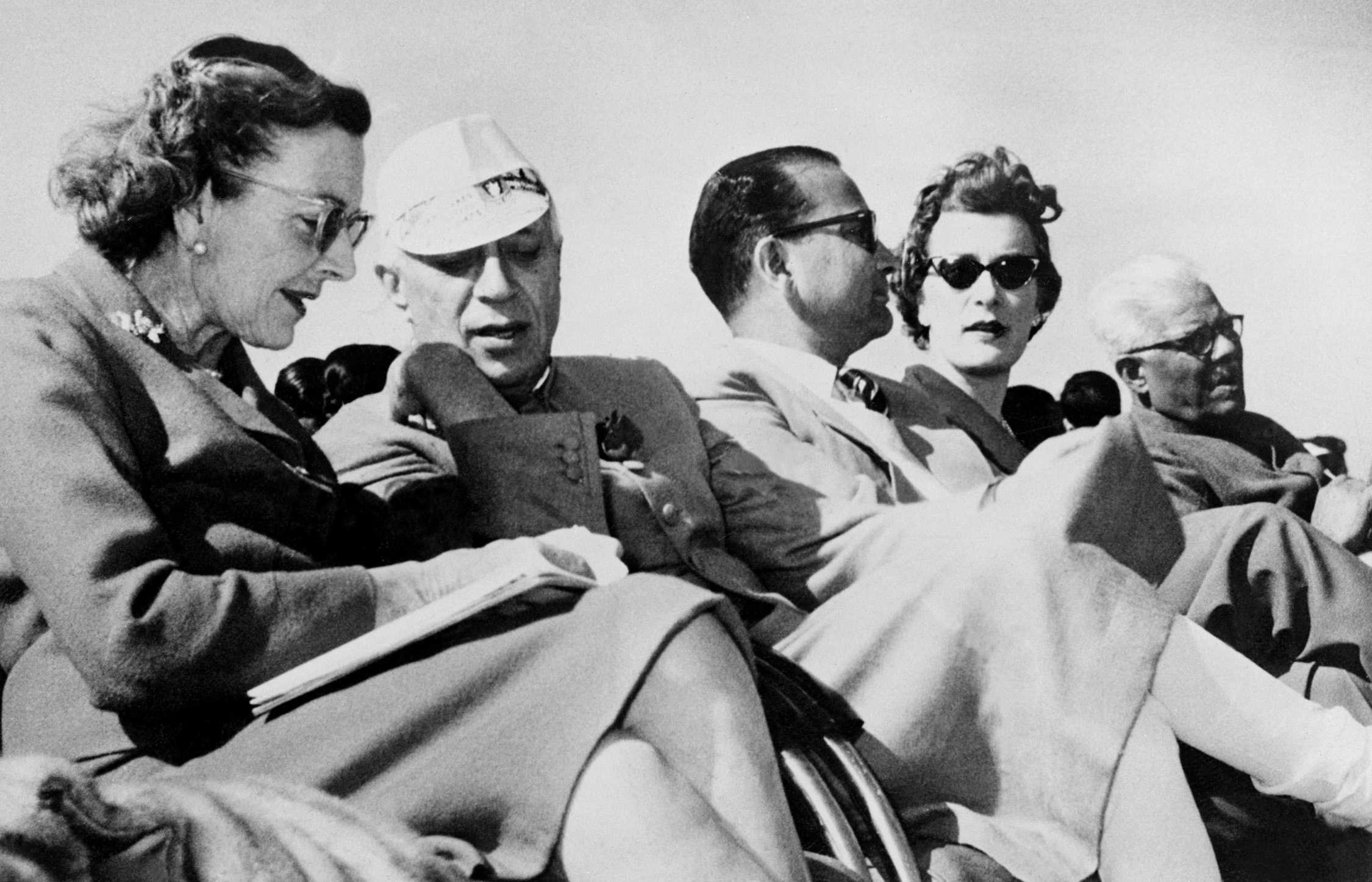 Taken on 27 February 1959, Lady Pamela Mountbatten is seen seated among distinguished company as Pandit Jawaharlal Nehru speaks with Lady Pamela's mothe, Lady Mountbatten, capturing a moment of international diplomacy during a New Delhi Glider Club display.