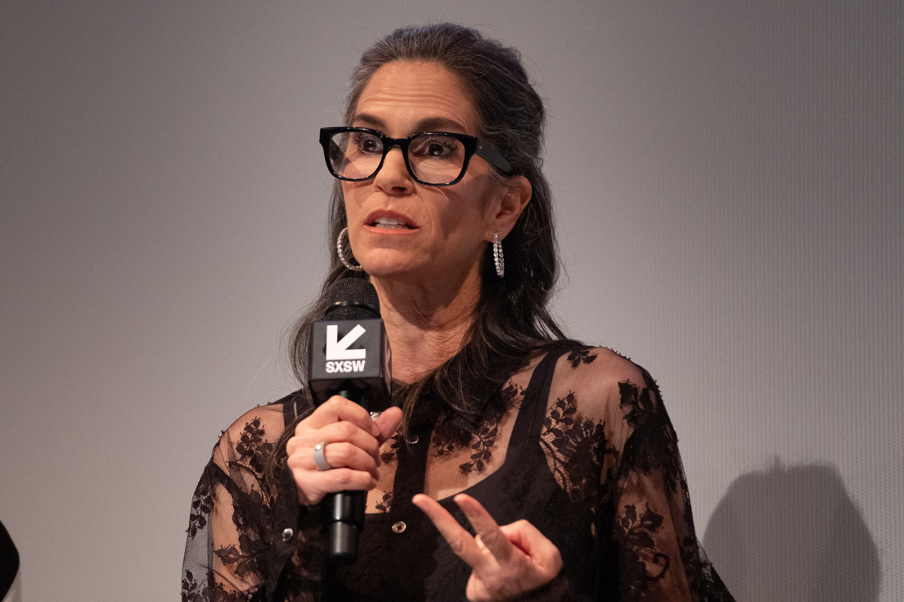Speaking on stage at SXSW, Jami Gertz wore bold glasses and a black lace top, gesturing passionately as she addressed the audience.