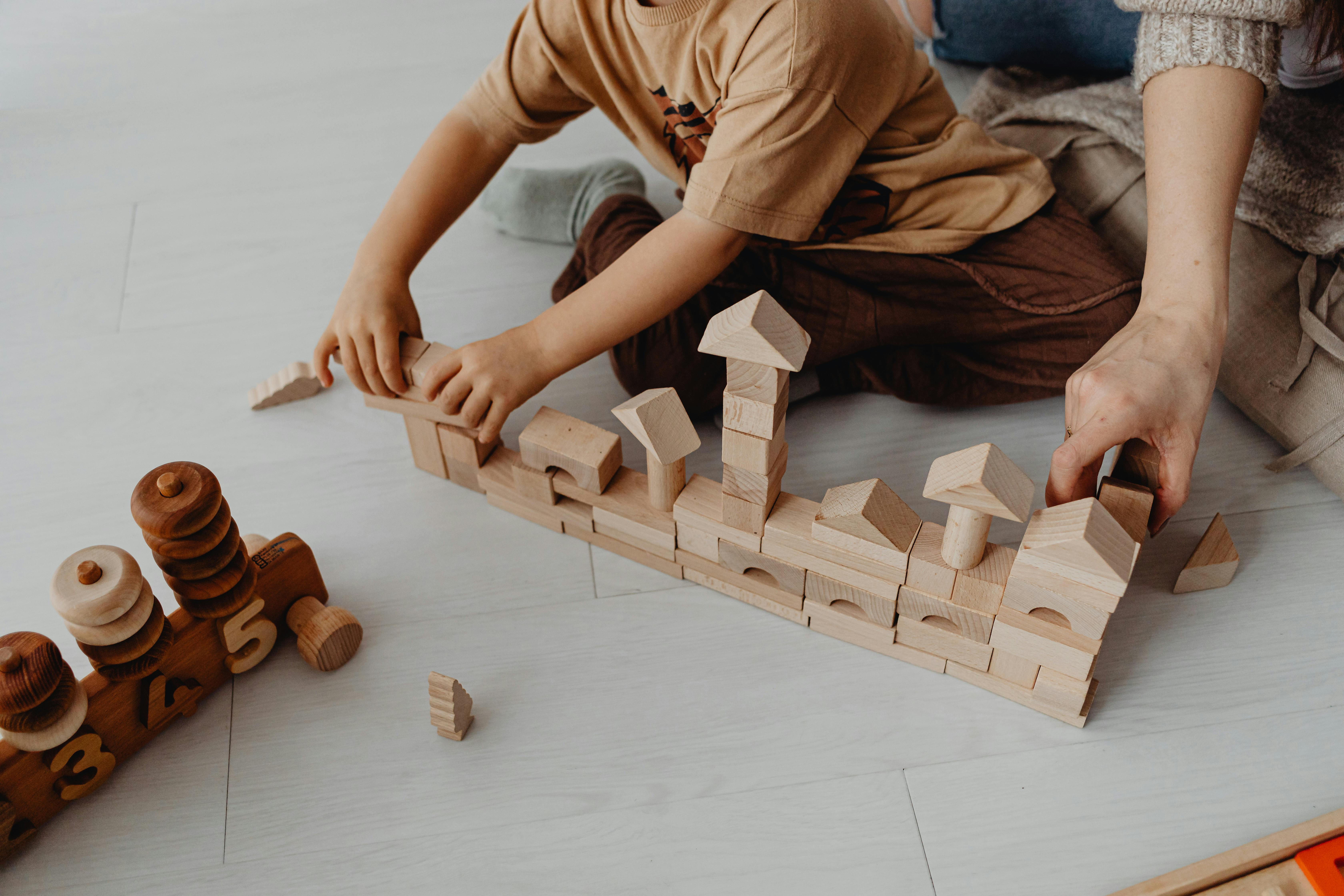 An adult playing with a baby and his toys | Source: Pexels