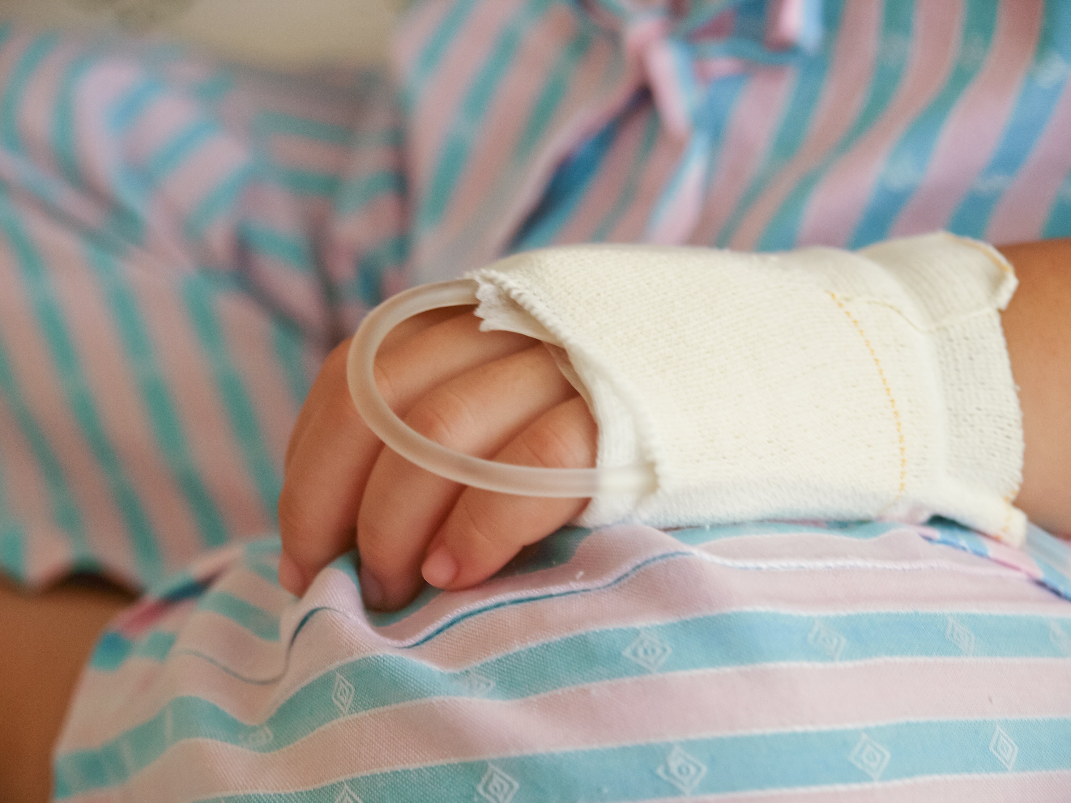 Hand des kranken kleinen Kindes im Krankenhausbett | Quelle: Shutterstock
