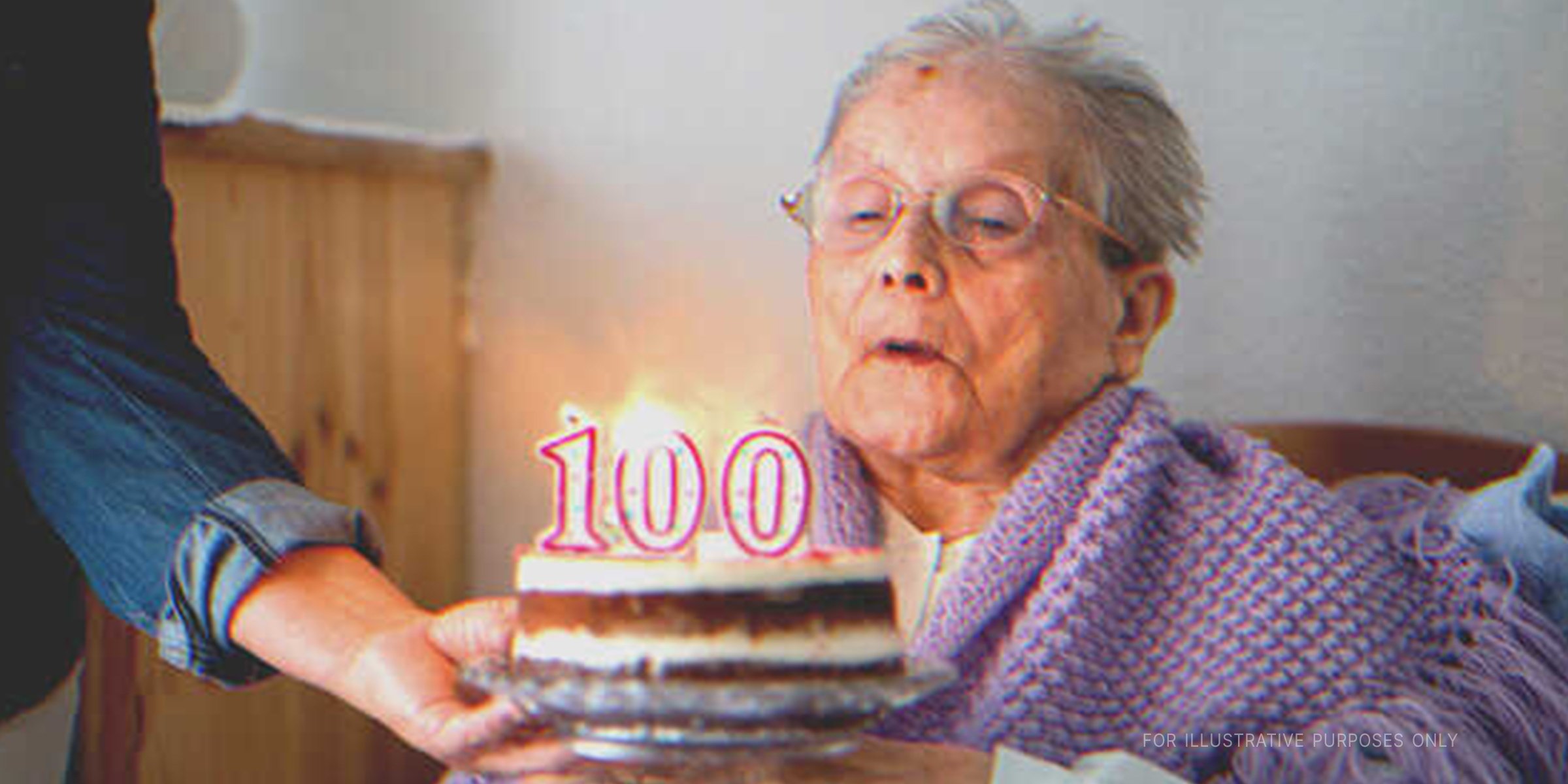 Older woman blowing birthday cake. | Getty Images