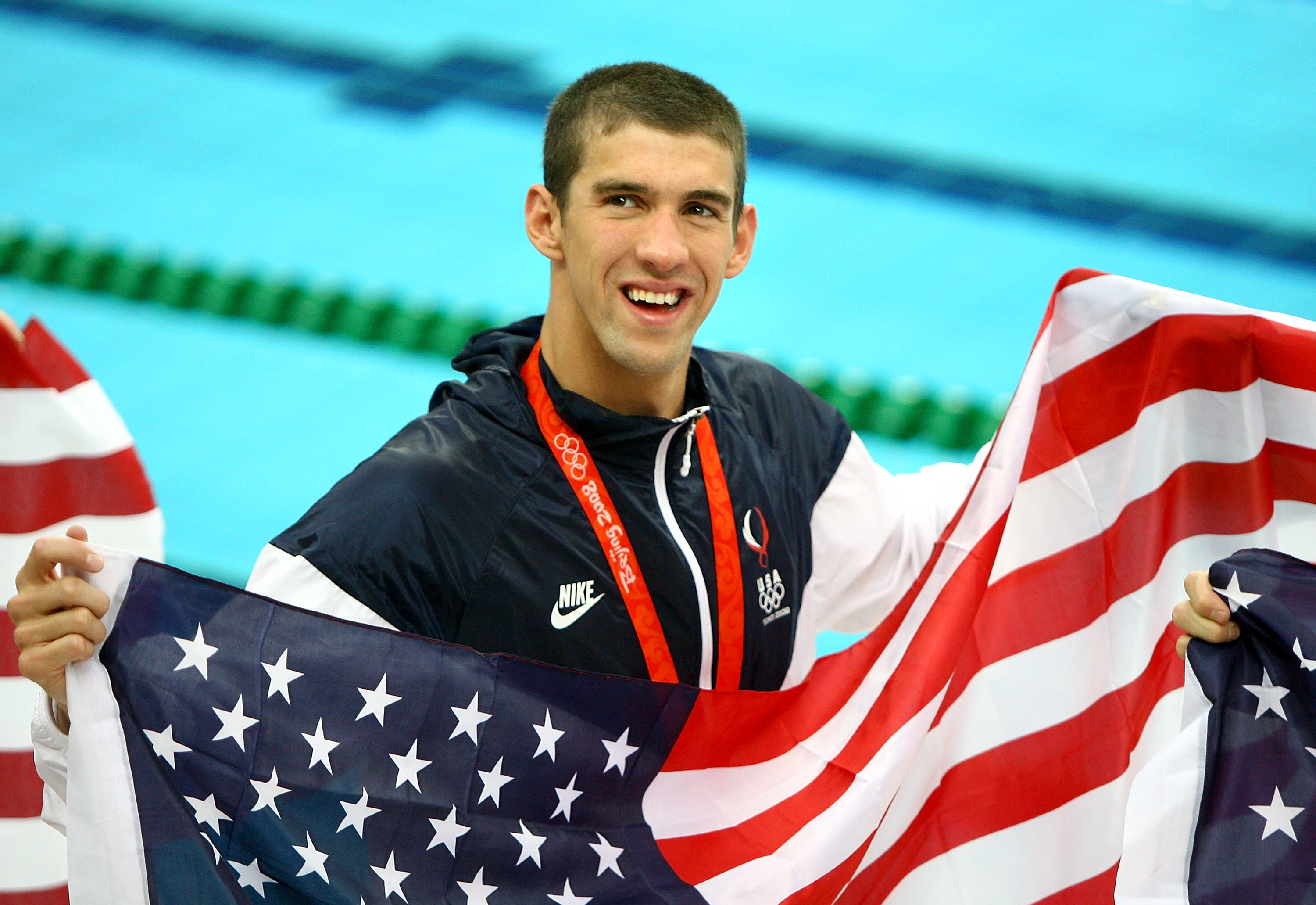 Michael Phelps proudly displays his eighth gold medal, wearing a smile and the American flag, following the Men's 4x100 Medley Relay at the Beijing 2008 Olympic Games on August 17, 2008, in Beijing, China | Source: Getty Images