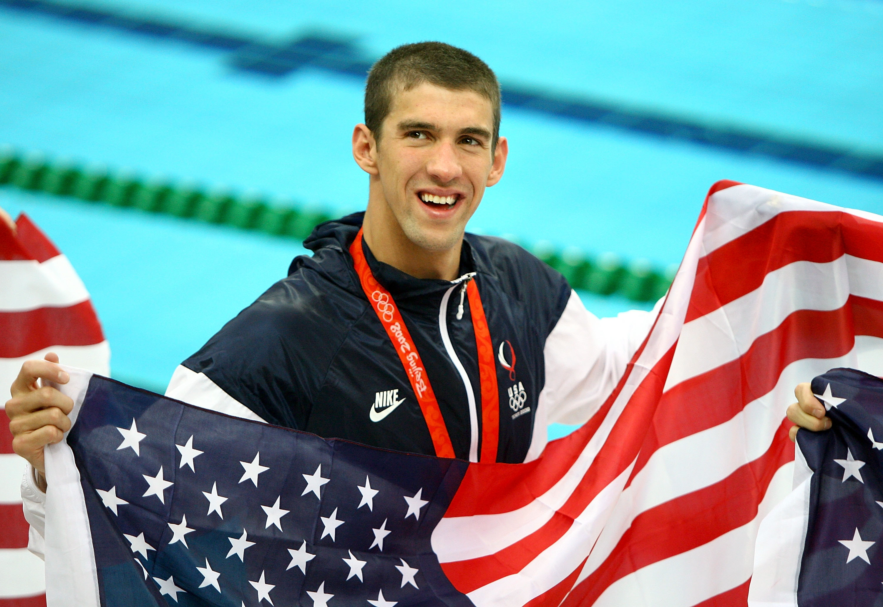 Michael Phelps proudly displays his eighth gold medal, wearing a smile and the American flag, following the Mens 4x100 Medley Relay at the Beijing 2008 Olympic Games on August 17, 2008, in Beijing, China | Source: Getty Images