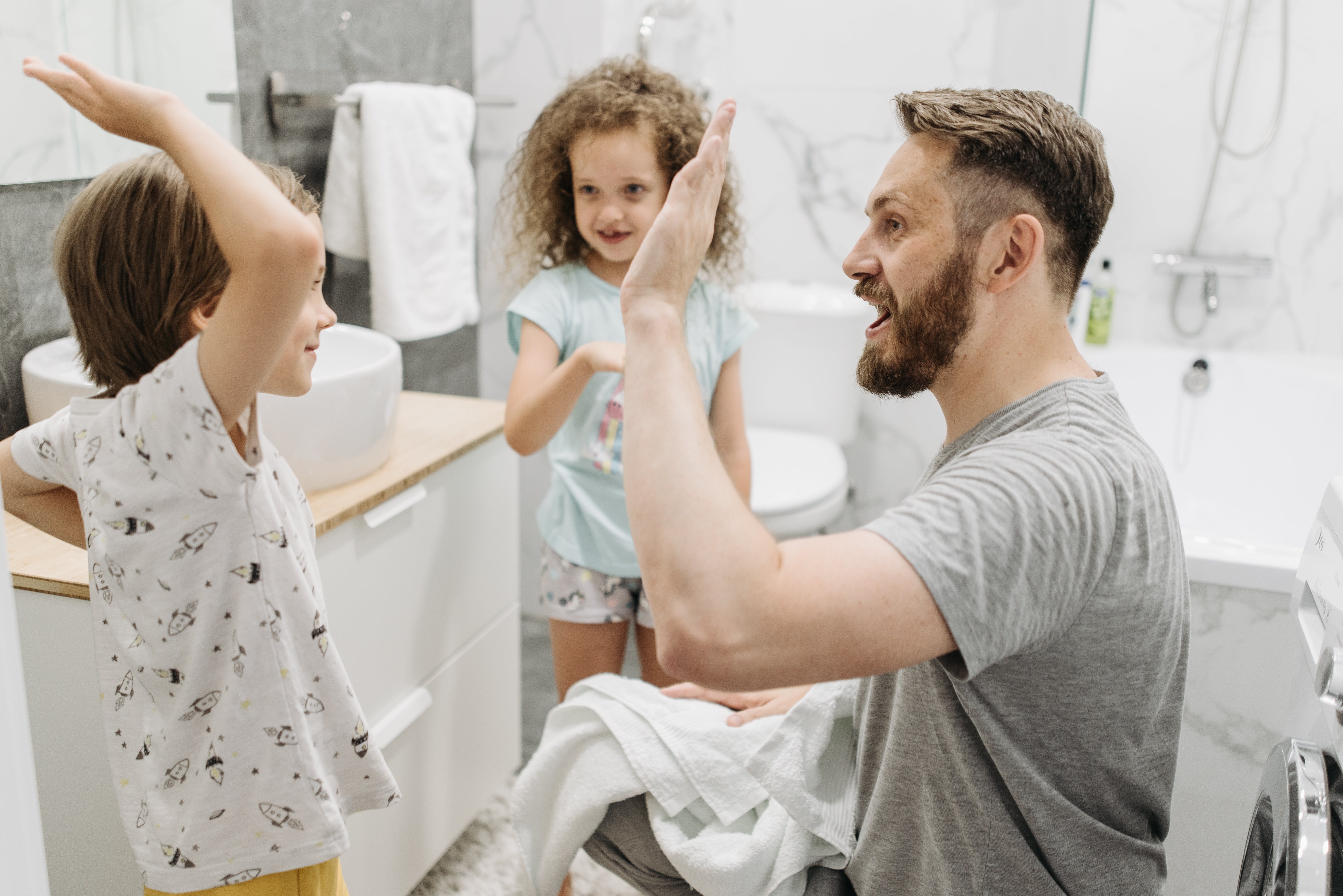 A man high-fiving a child while another looks on while in the bathroom | Source: Pexels