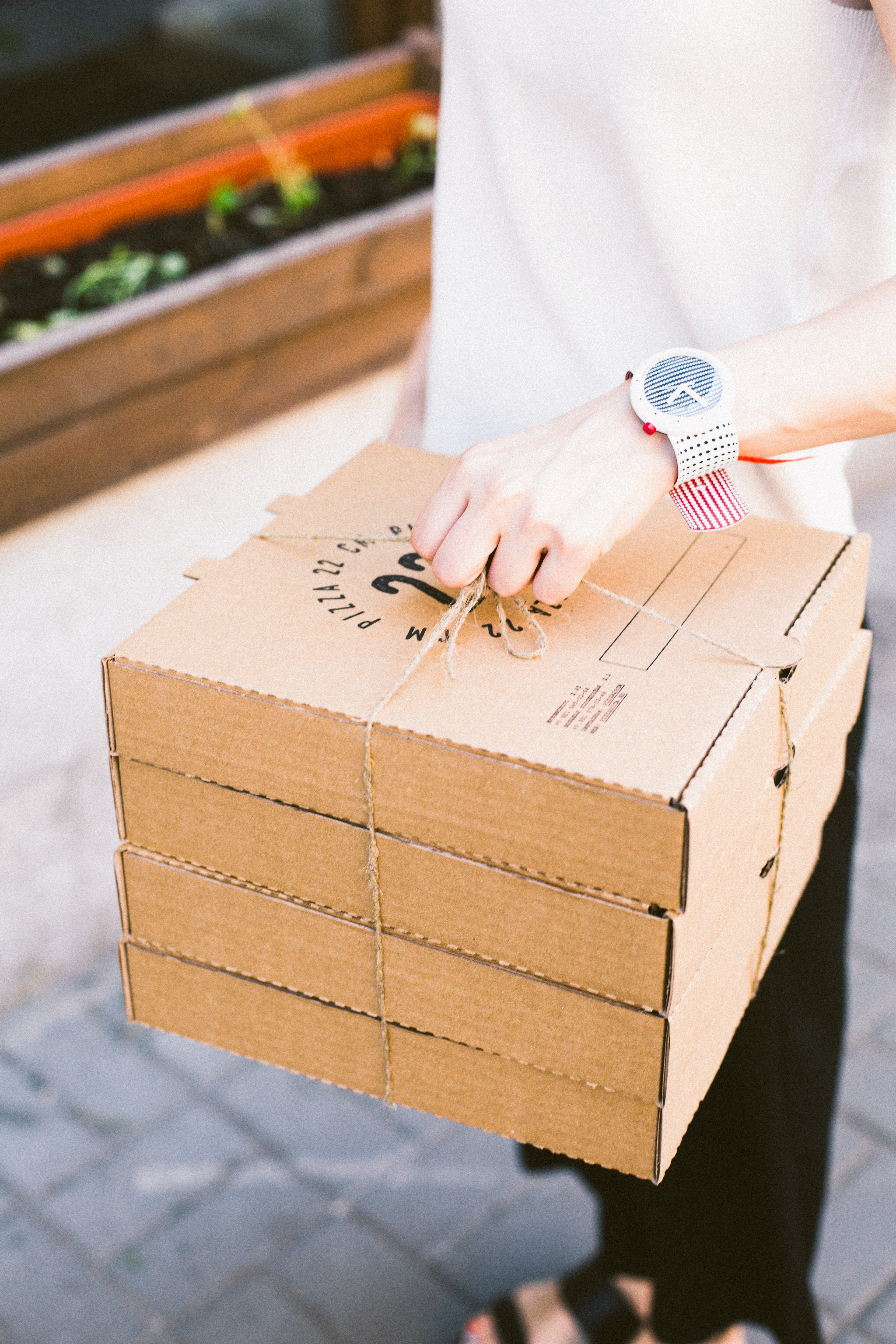Person in a white shirt holding a stack of pizza boxes | Photo: Pexels