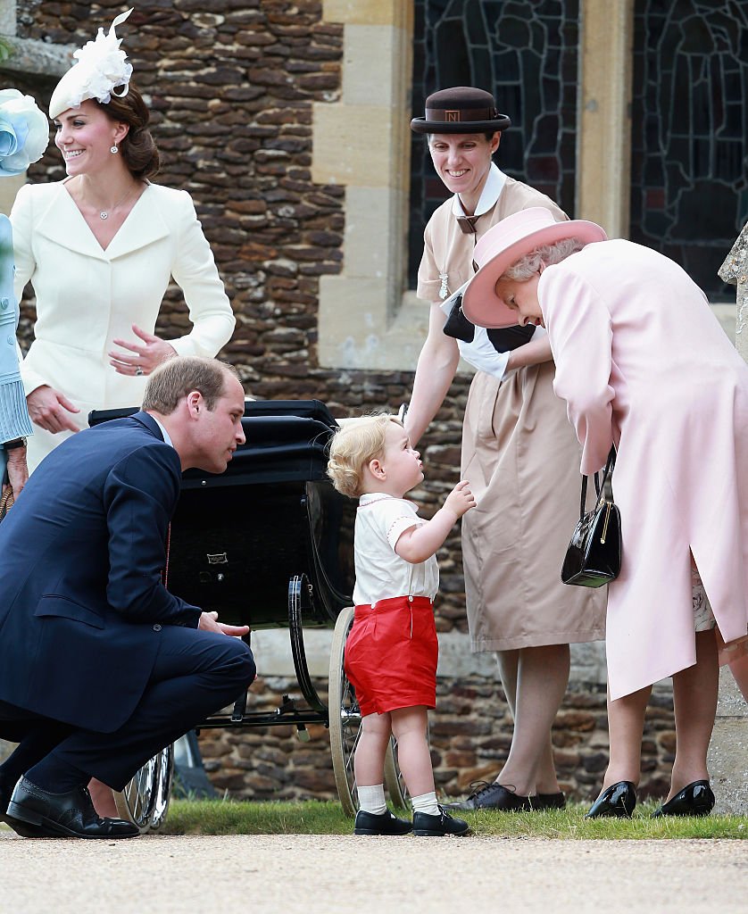 Catherine, duchesse de Cambridge, le prince William, duc de Cambridge, la princesse Charlotte de Cambridge et le prince George de Cambridge, la reine Elizabeth II et la nounou du prince George, Maria Teresa Turrion Borrallo quittent l'église Sainte-Marie-Madeleine sur le domaine de Sandringham pour le baptême de La princesse Charlotte de Cambridge le 5 juillet 2015 à King's Lynn, en Angleterre. І Source : Getty Images