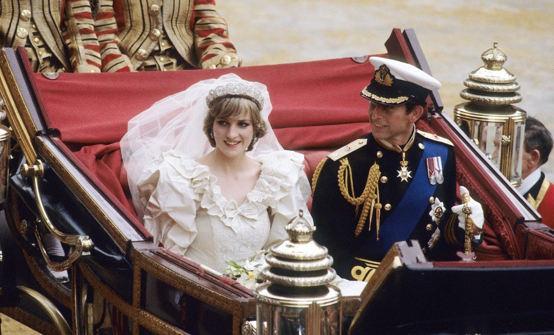 Prince Charles, Prince of Wales and Diana, Princess of Wales, wearing a wedding dress designed by David and Elizabeth Emanuel and the Spencer family Tiara, ride in an open carriage, from St. Paul's Cathedral to Buckingham Palace, following their wedding on July 29, 1981 in London, England. | Source: Getty Images