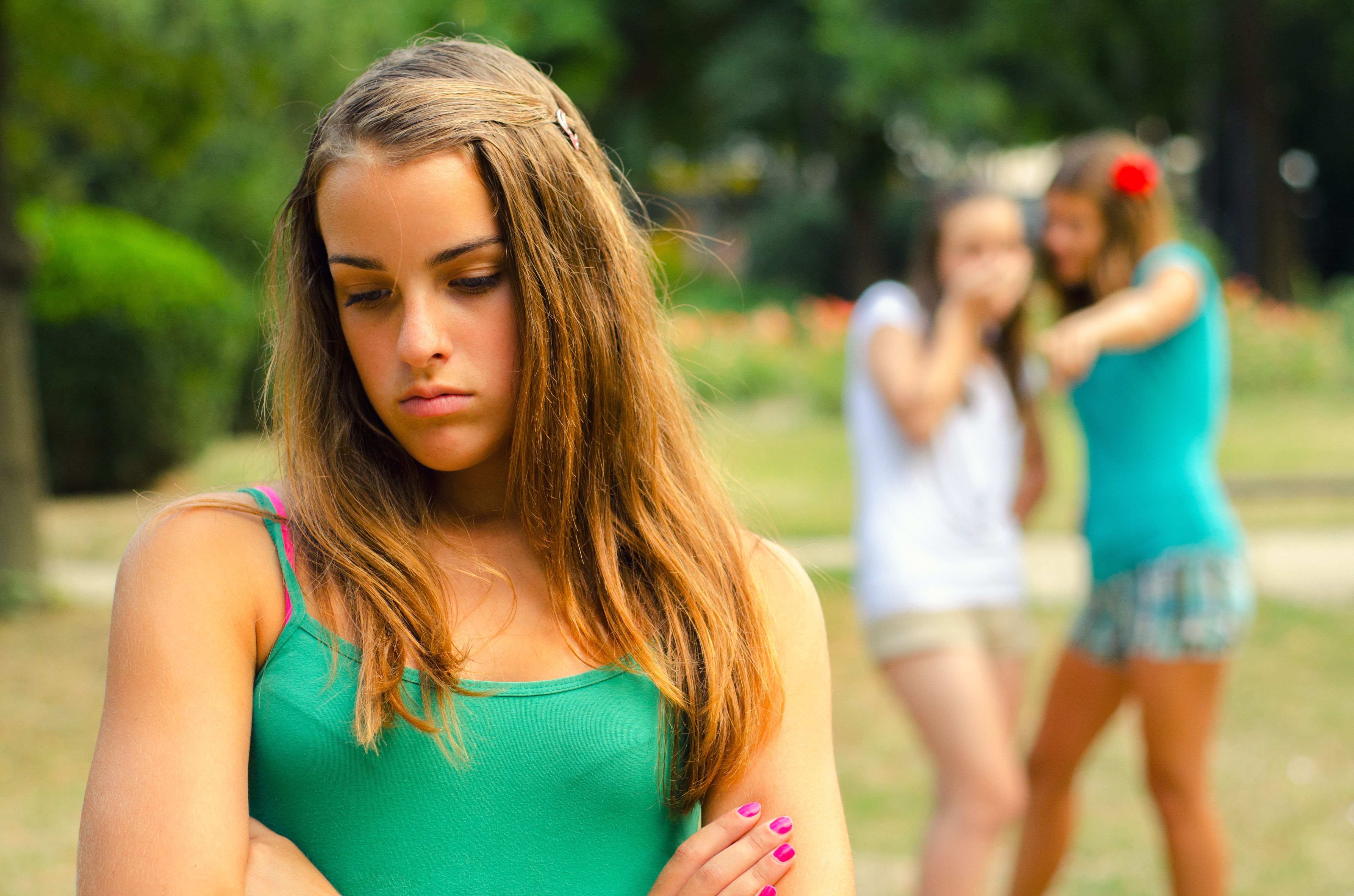 A teen looks sad while her peers tease her. | Source: Shutterstock