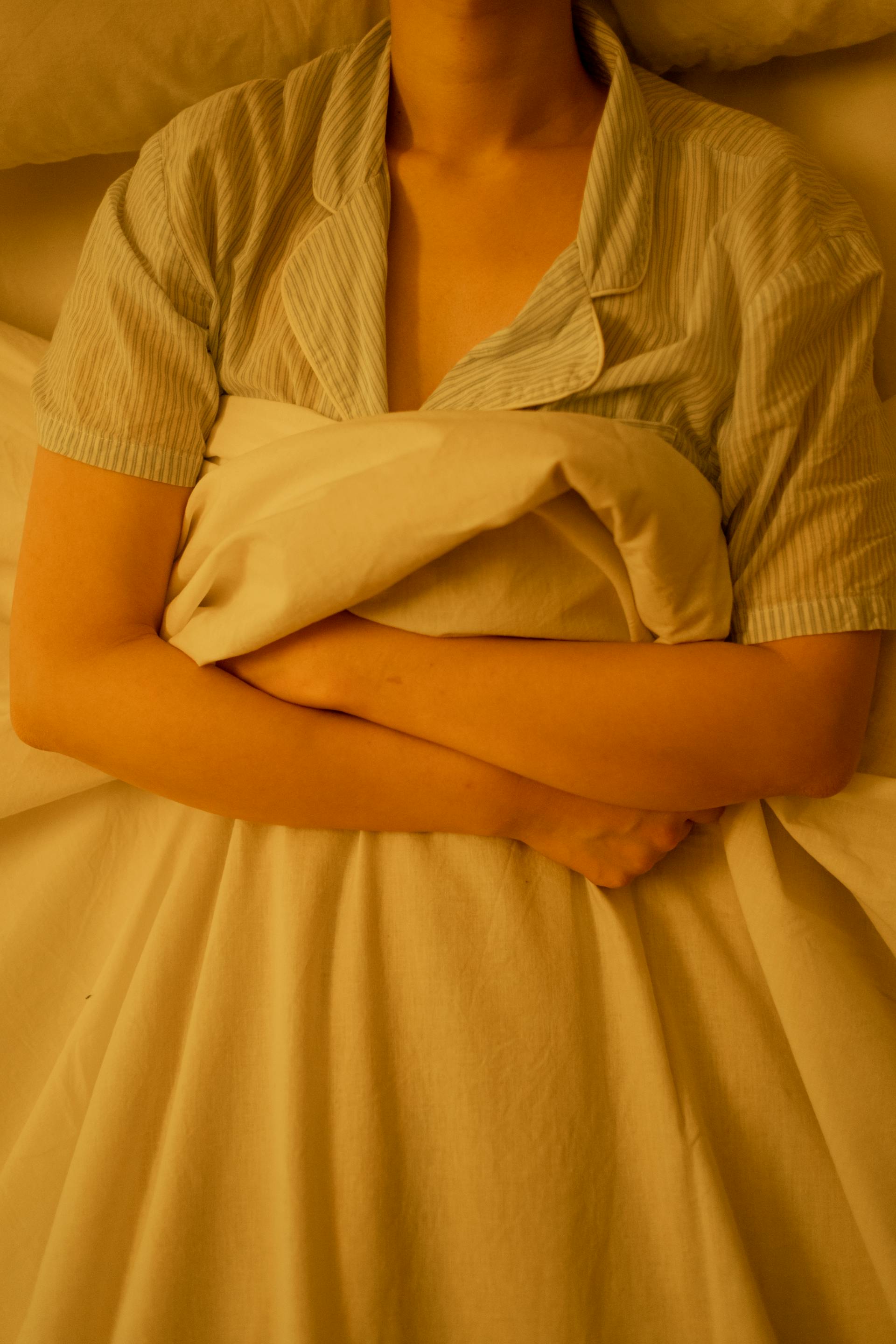 A woman lying in bed grasping a blanket | Source: Pexels