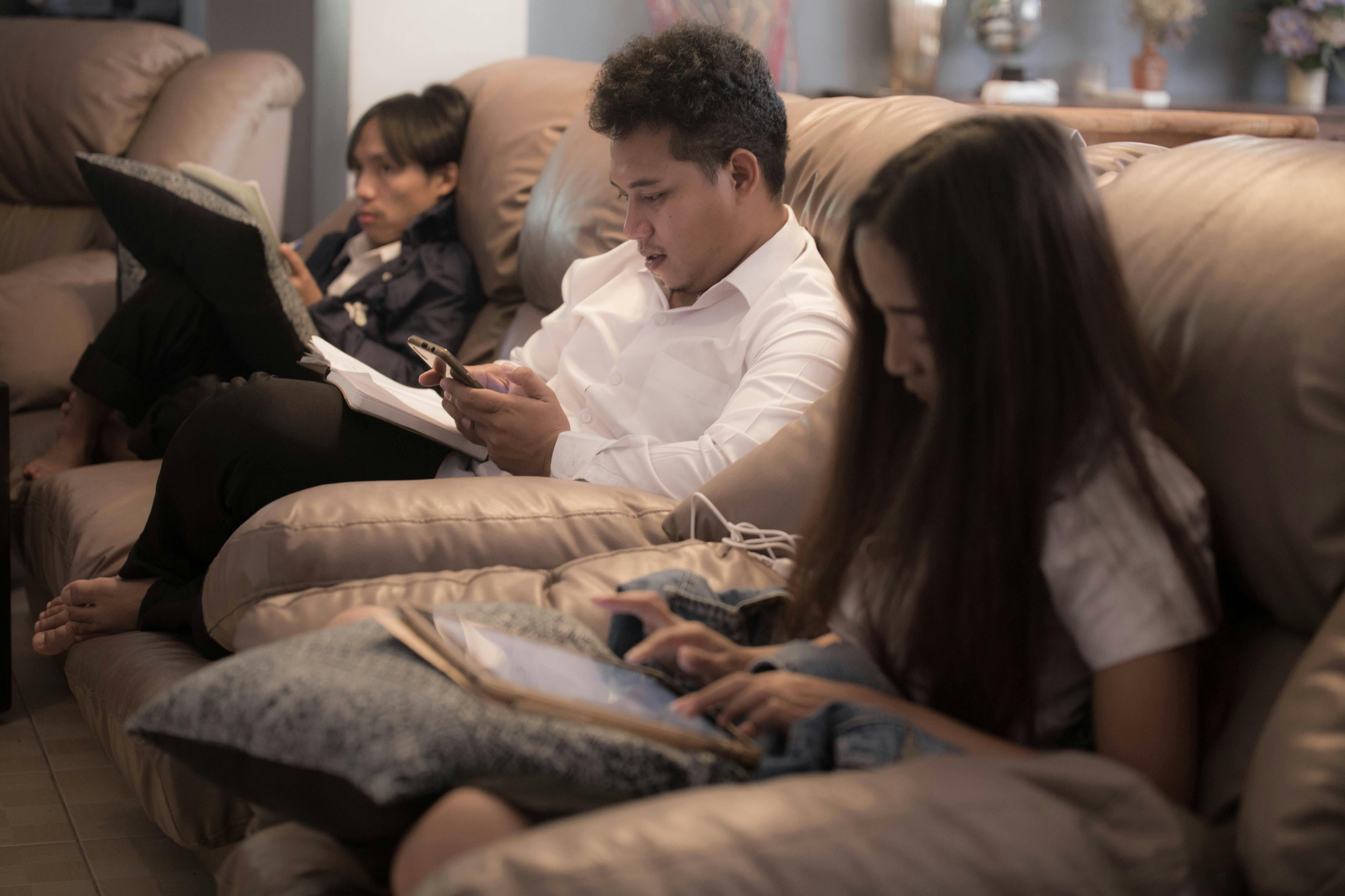 People sitting on a couch with their devices | Source: Pexels