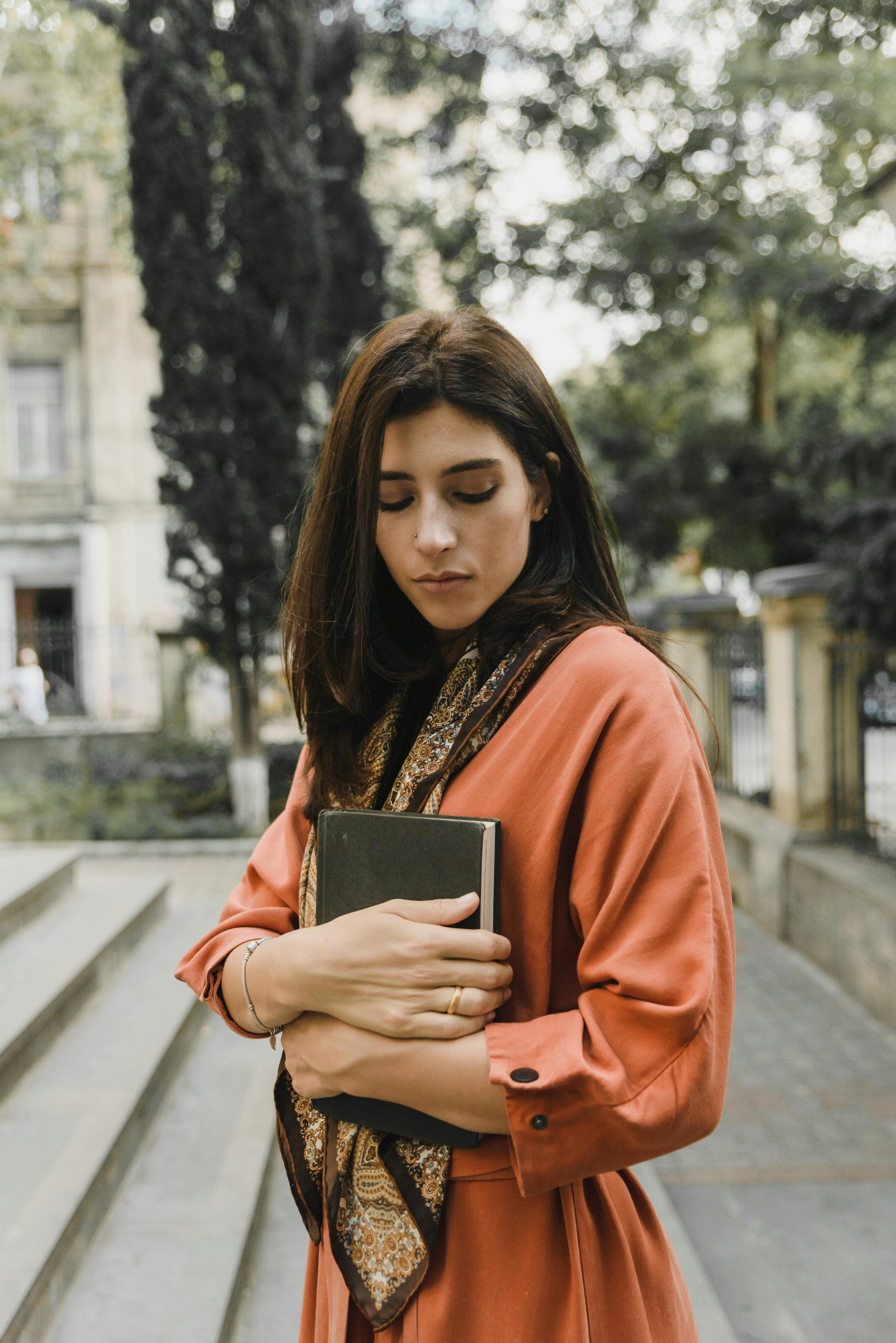 A sad woman looking down while holding a book | Source: Pexels