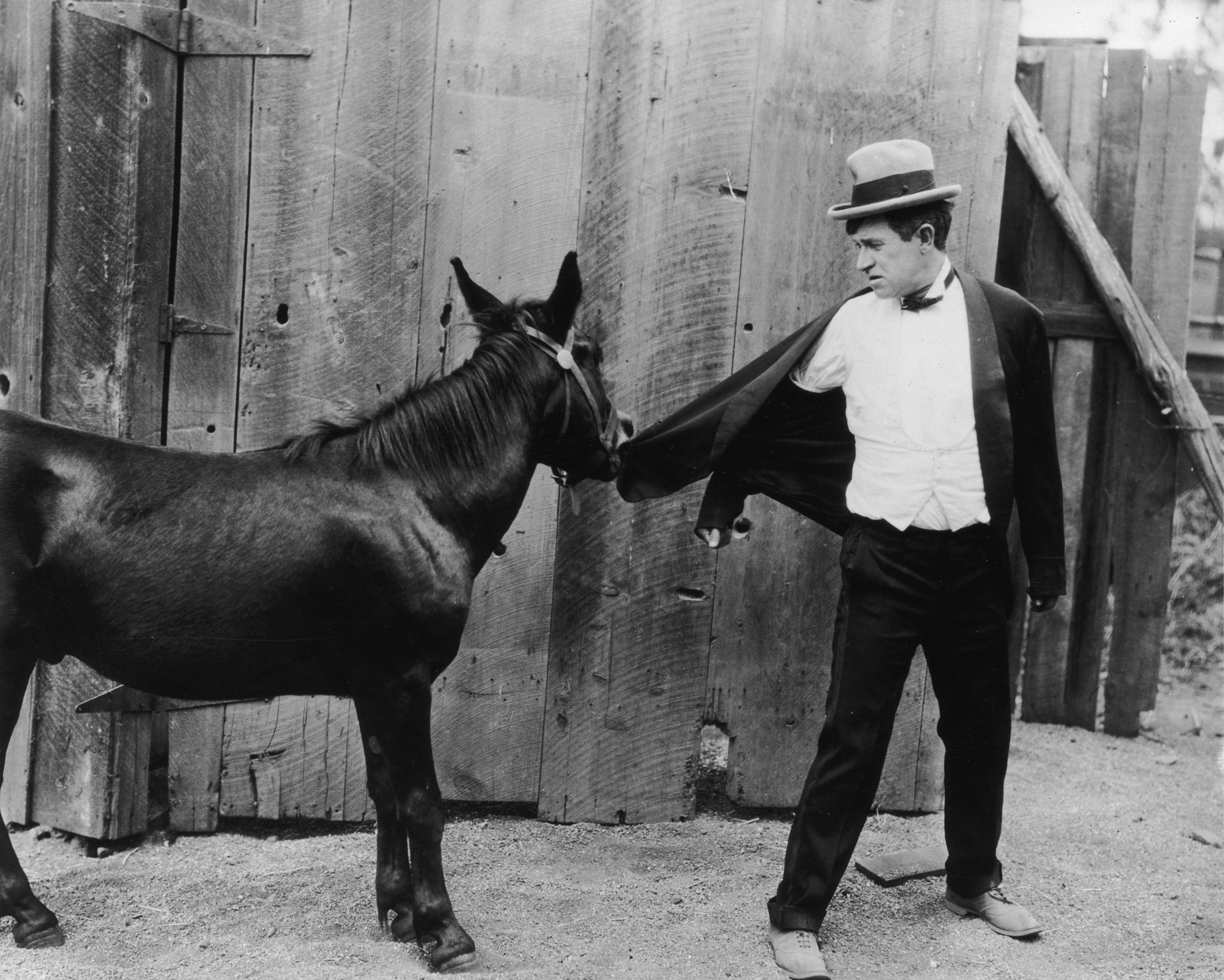 circa 1925: Amerikanischer Schauspieler und Comedian Will Rogers (1879-1935) schaut zurück, während ein Eisel sein Jackett festhält in einem nicht identifizierten Filmausschnitt. | Foto von: American Stock/Getty Images
