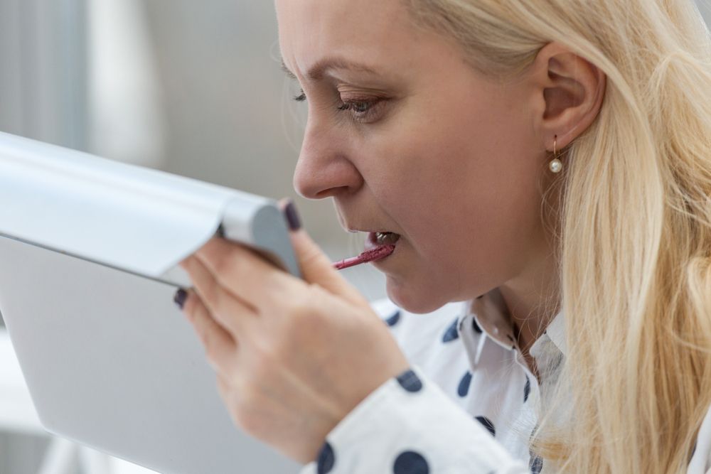 Une femme se mettant du lipstick. l Source : Shutterstock