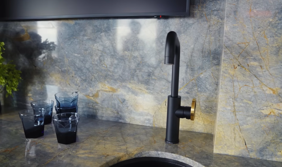 Even the bar has its own show stopping stone, paired with a sculptural black tap and smoky blue glasses. Christopher's claim that every room features a different marble suddenly does not sound exaggerated at all. | Source: YouTube/Architectural Digest
