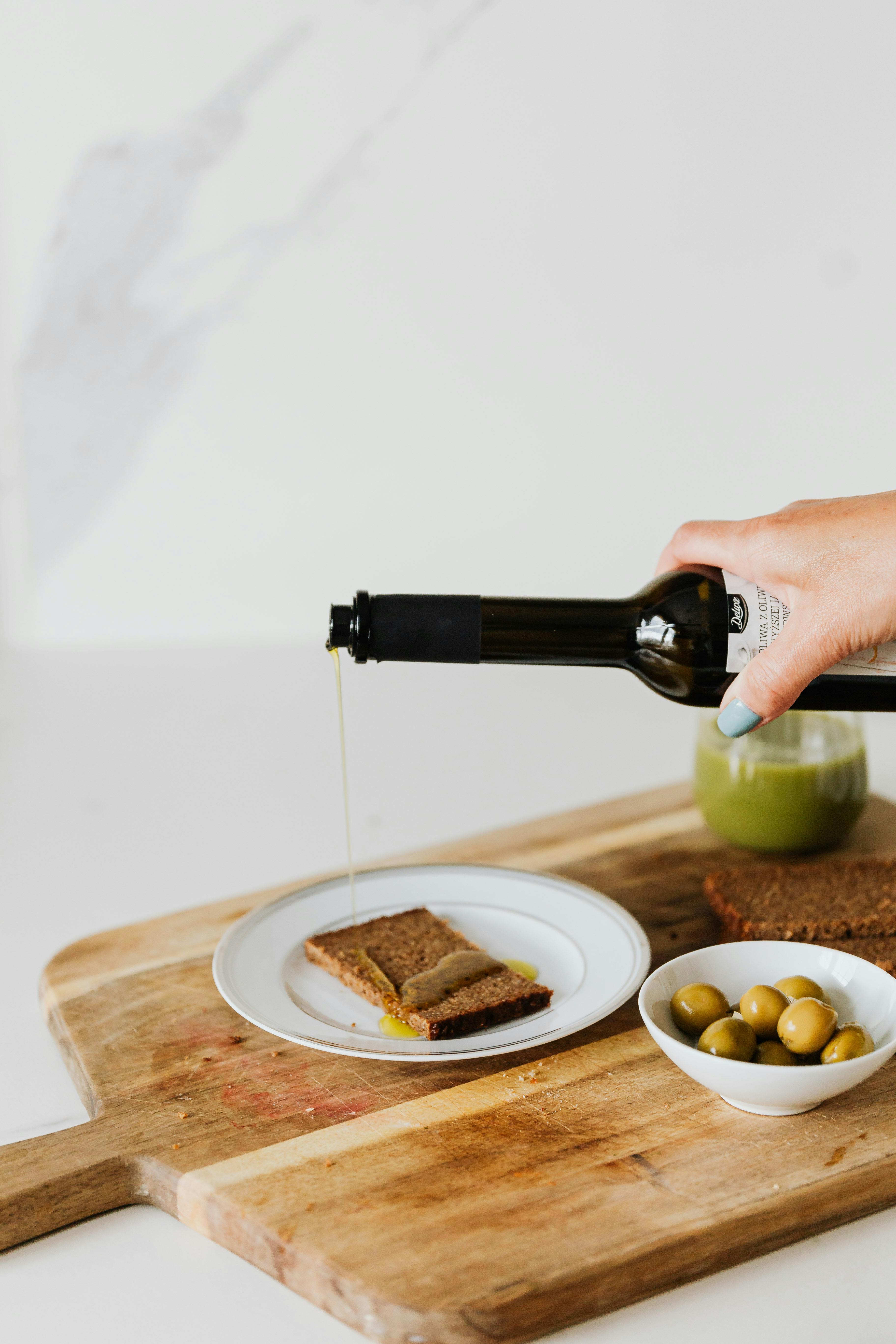 A person pouring olive oil on bread | Source: Pexels