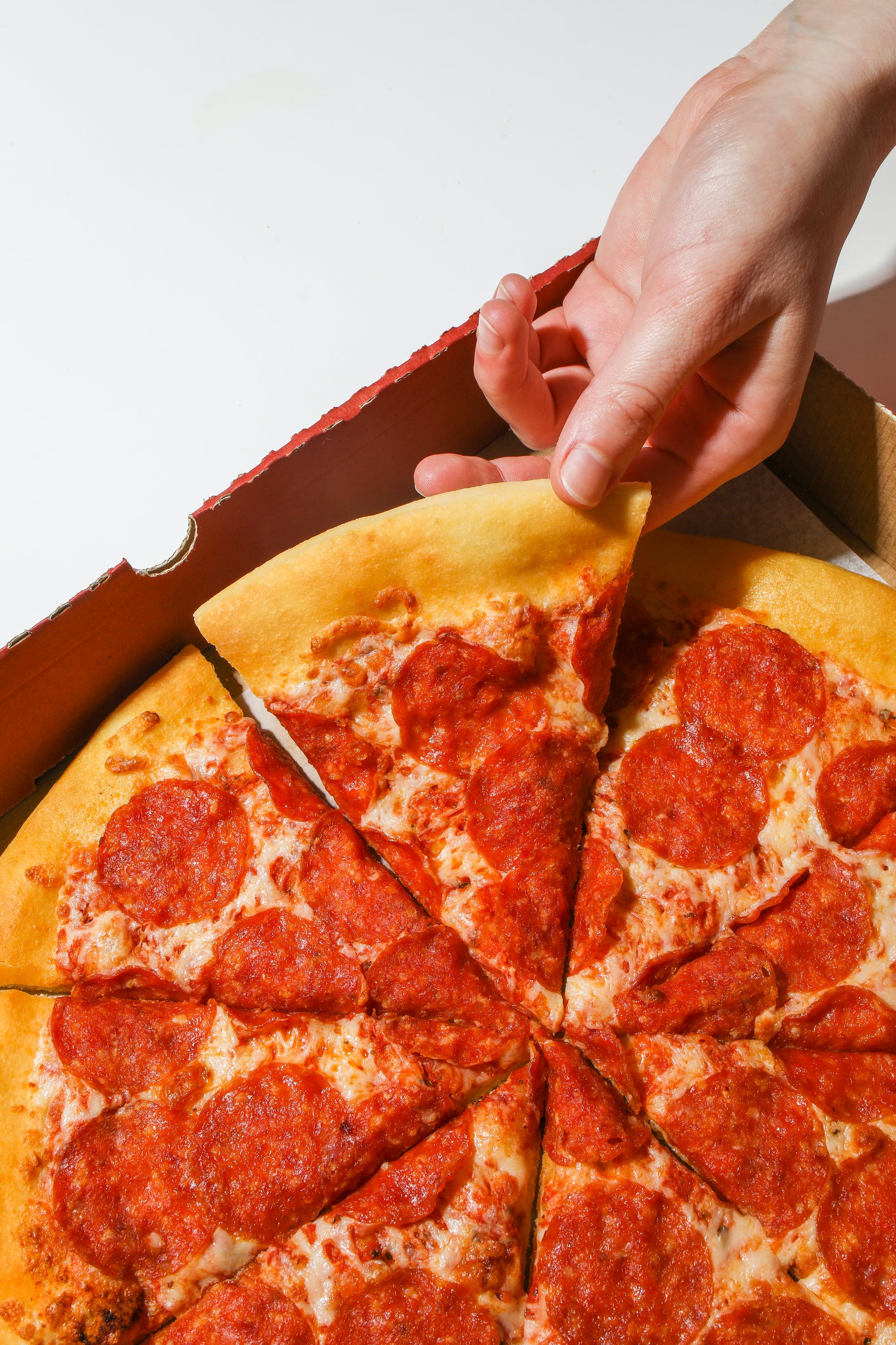 A person holding a slice of pizza. | Source: Pexels