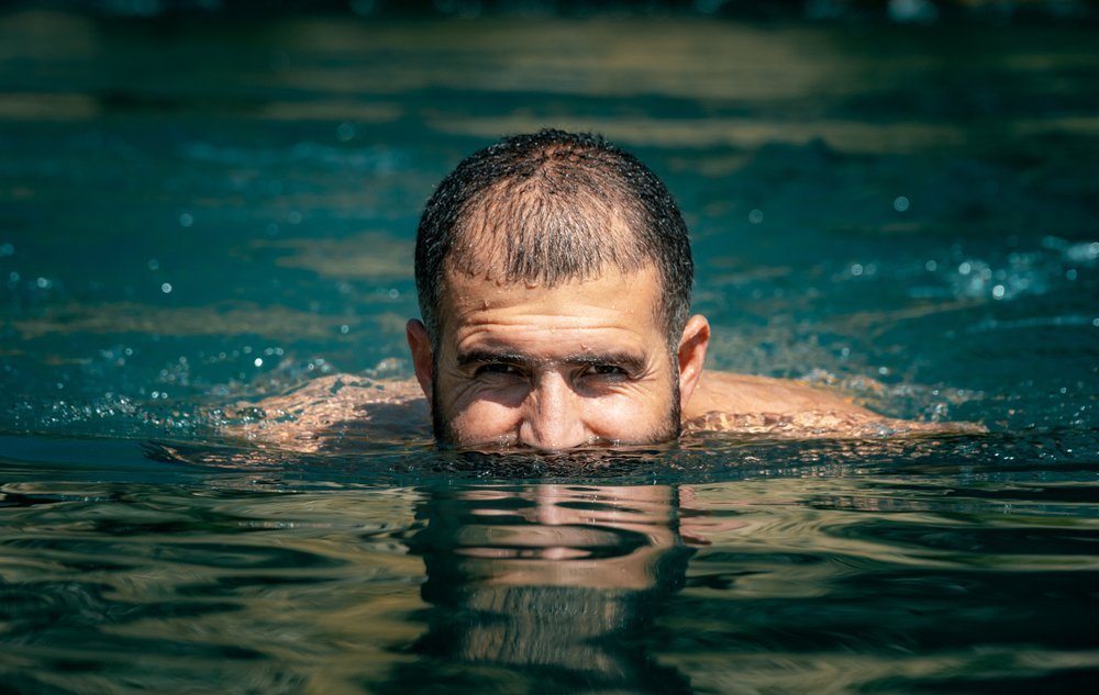 A photo of a man swimming with his face above water. | Photo: Shutterstock
