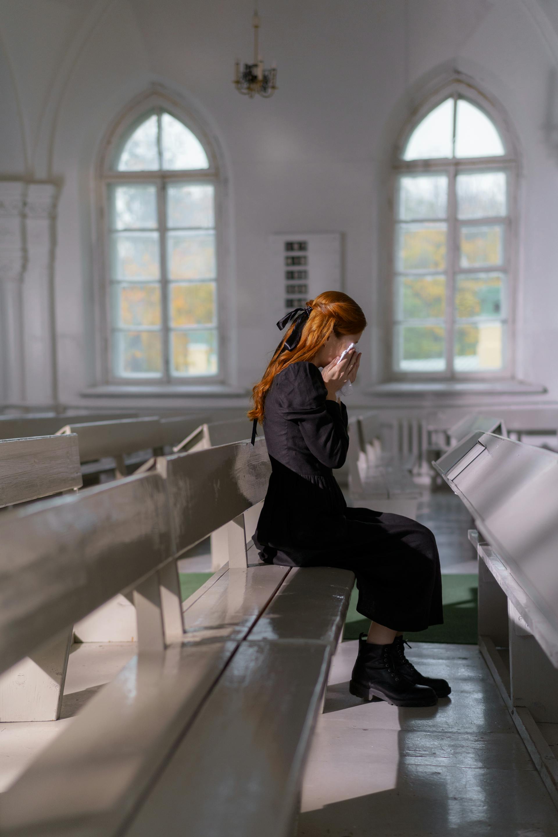 A young woman sitting inside the church and mourning | Source: Pexels