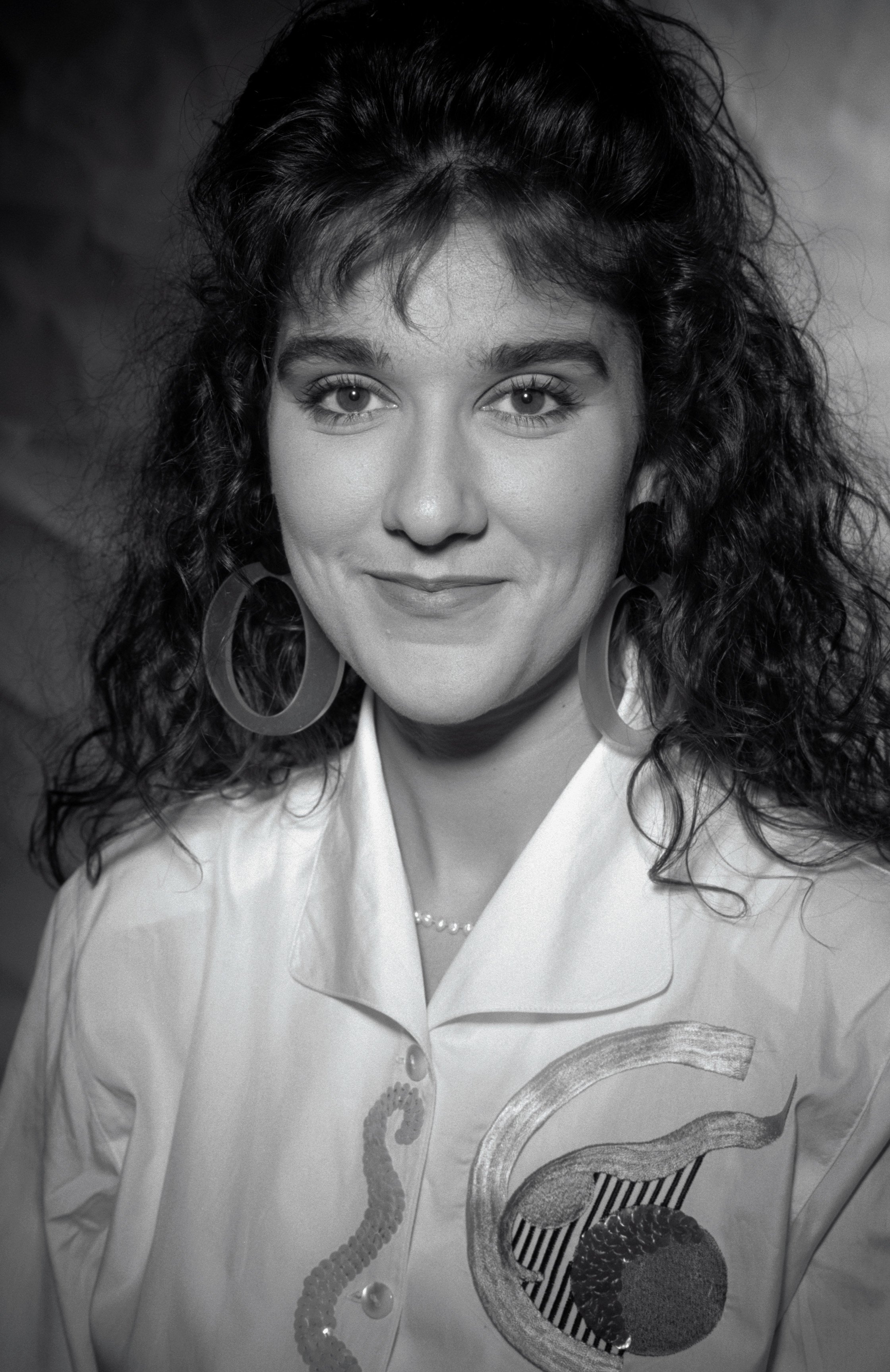 Canadian singer Celine Dion pictured wearing a white blouse with hoop earrings in 1991 in London. / Source: Getty Images