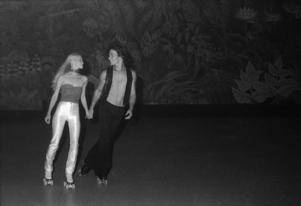 Patrick Swayze toma de la mano y patina con Lisa Niemi en la fiesta de estreno de la película 'Skatetown USA' en la pista de patinaje Flippers, Los Ángeles, California, octubre de 1979. | Foto: Getty Images