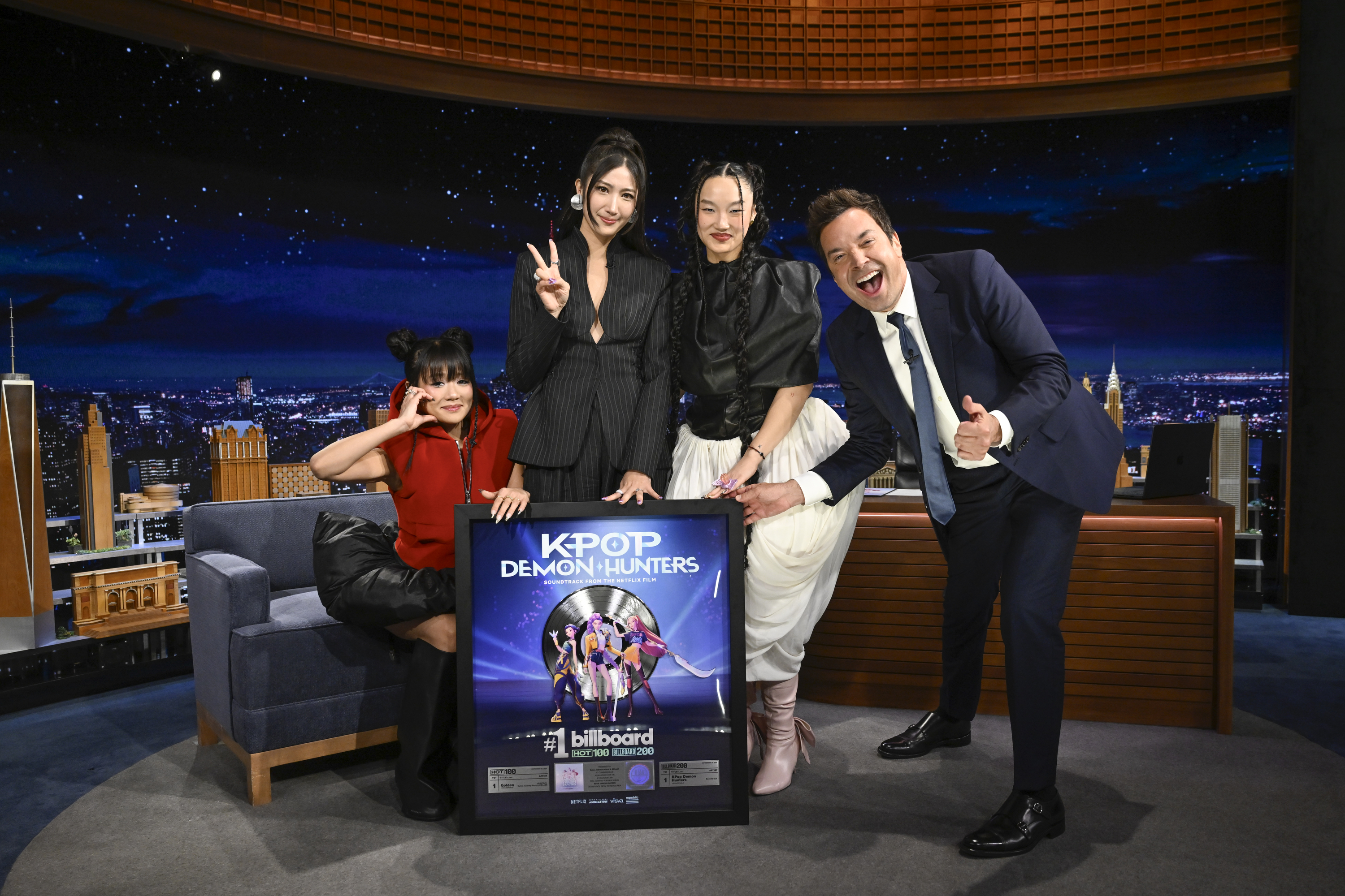 Rei Ami, Ejae, and Audrey Nuna of "K-Pop Demon Hunters" pose with host Jimmy Fallon and their platinum record on Tuesday, October 7, 2025. | Source: Getty Images