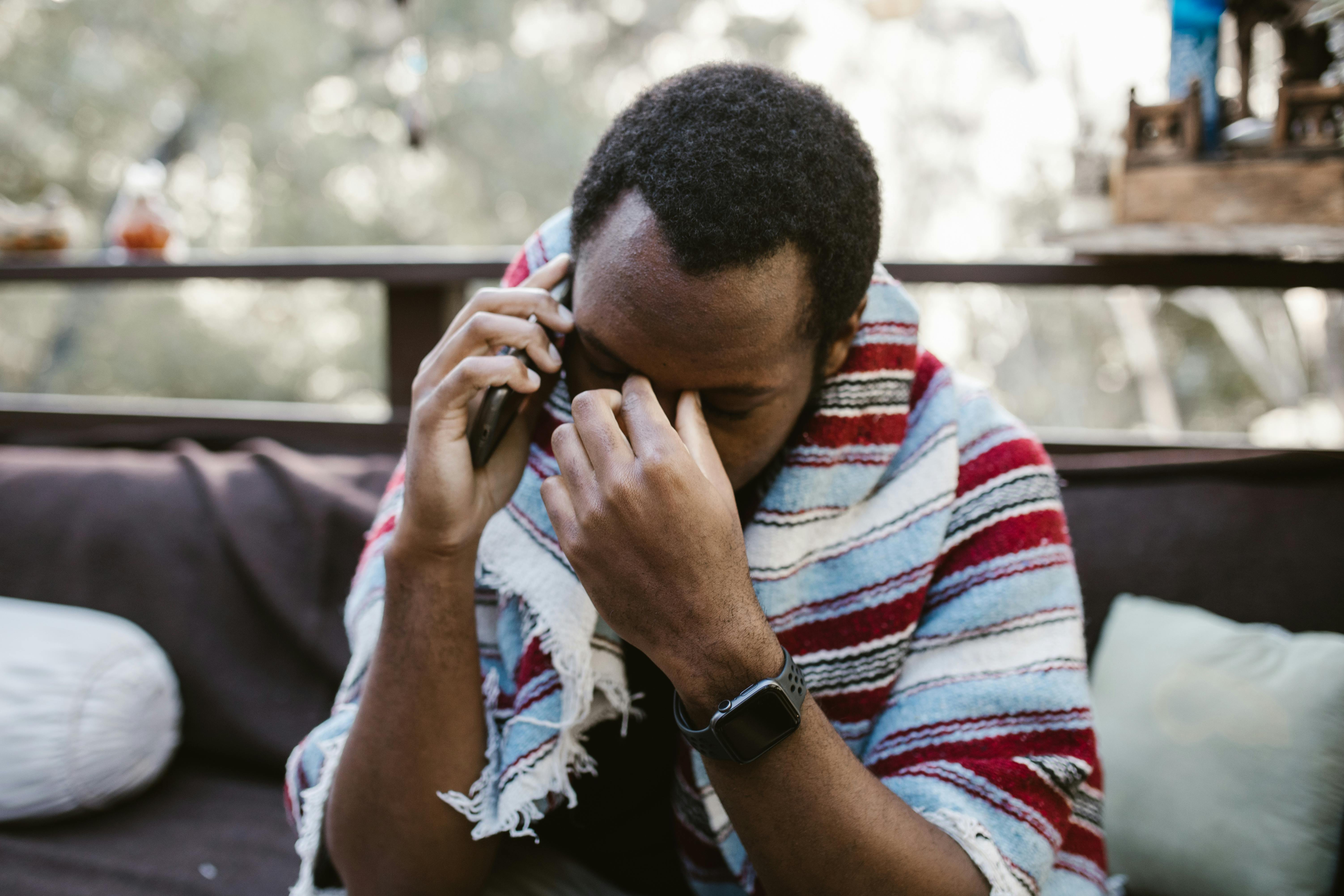 A frustrated man with his hand on his upper temple while talking on the phone | Source: Pexels