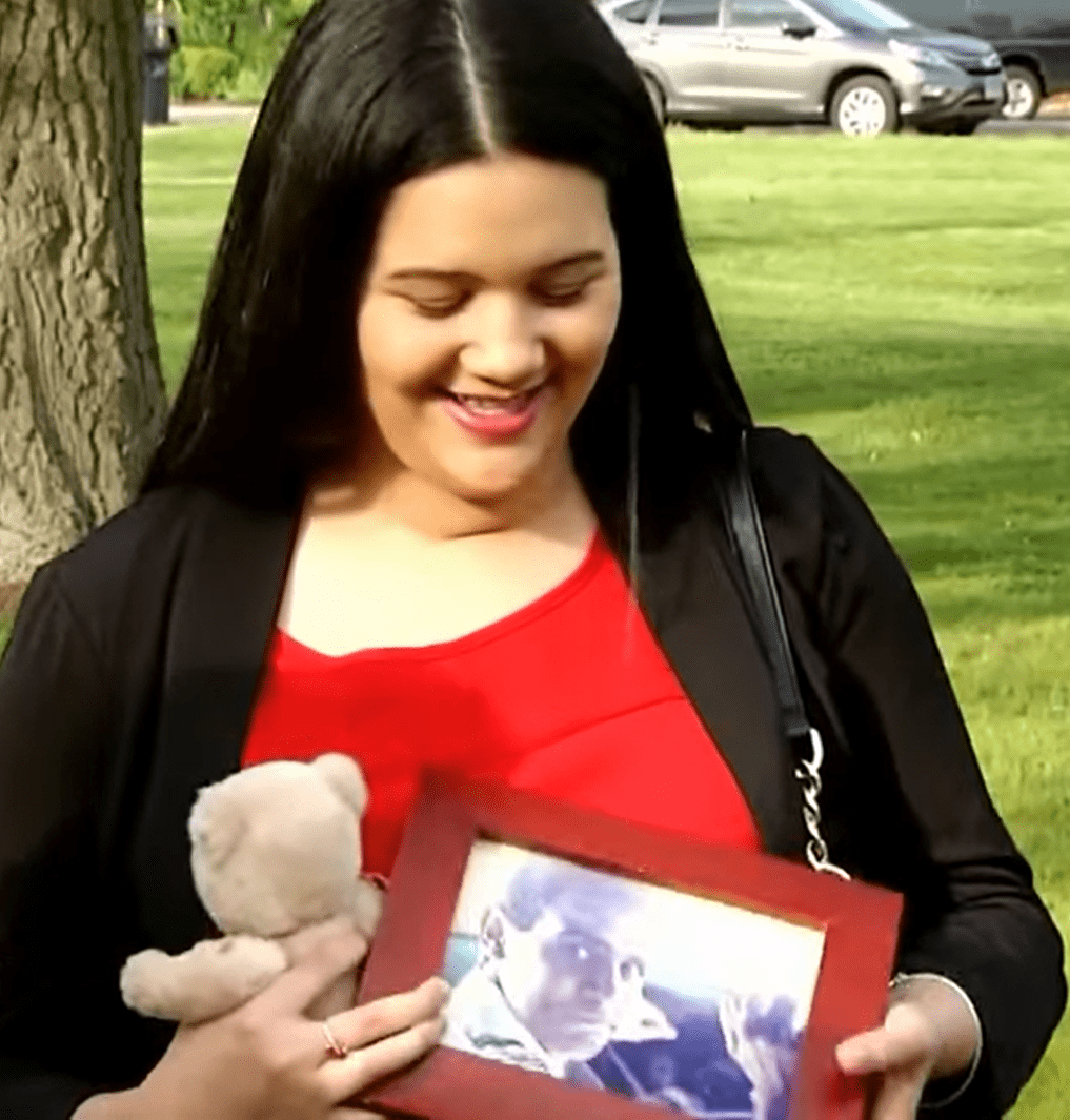 Josibelk Aponte smiling and holding a portrait frame of Peter Getz and a teddy bear he gave to her years back. | Source: youtube.com/Inside Edition