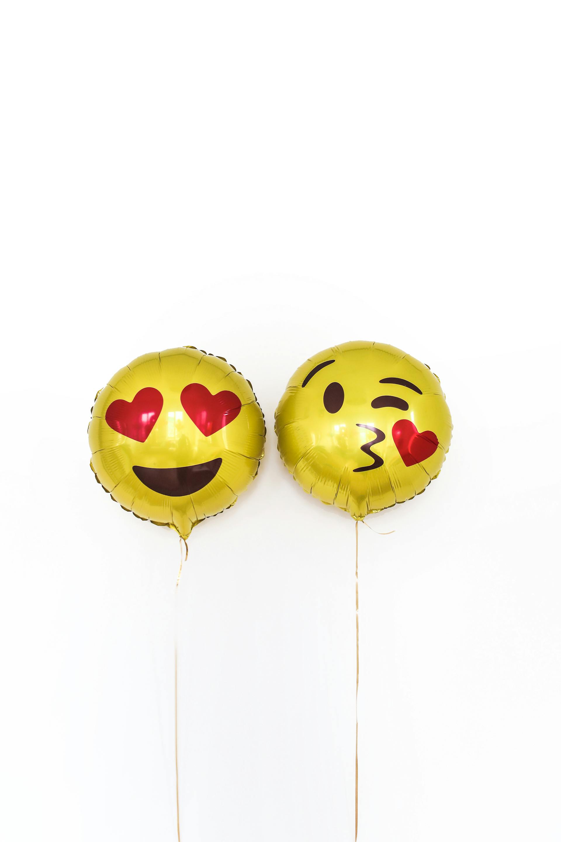 Two yellow balloons with emoji icons | Source: Pexels